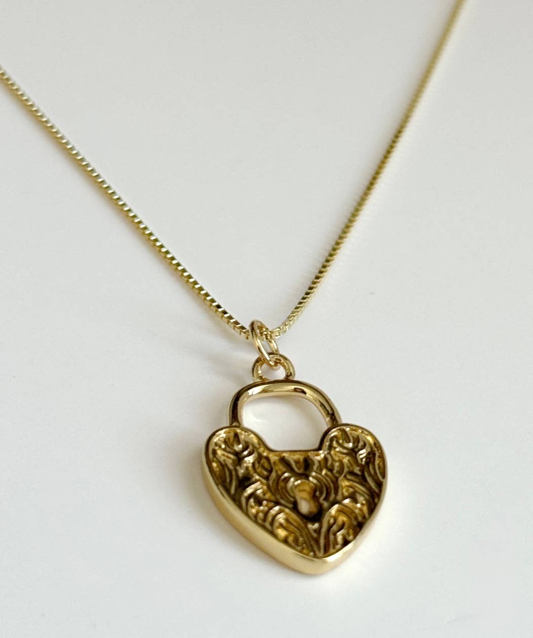 The Since Ive Been Loving You Necklace by Tramps+Thieves is a gold vermeil fine chain necklace featuring a heart-shaped locket with ornate floral engravings, displayed on a white background.
