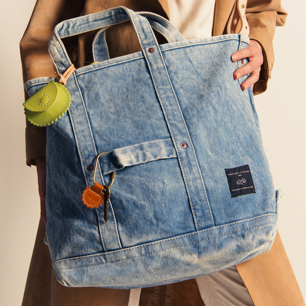 Person holding Electrician Tote | Acid Wash, a large acid wash denim canvas bag with leather and brass accents.