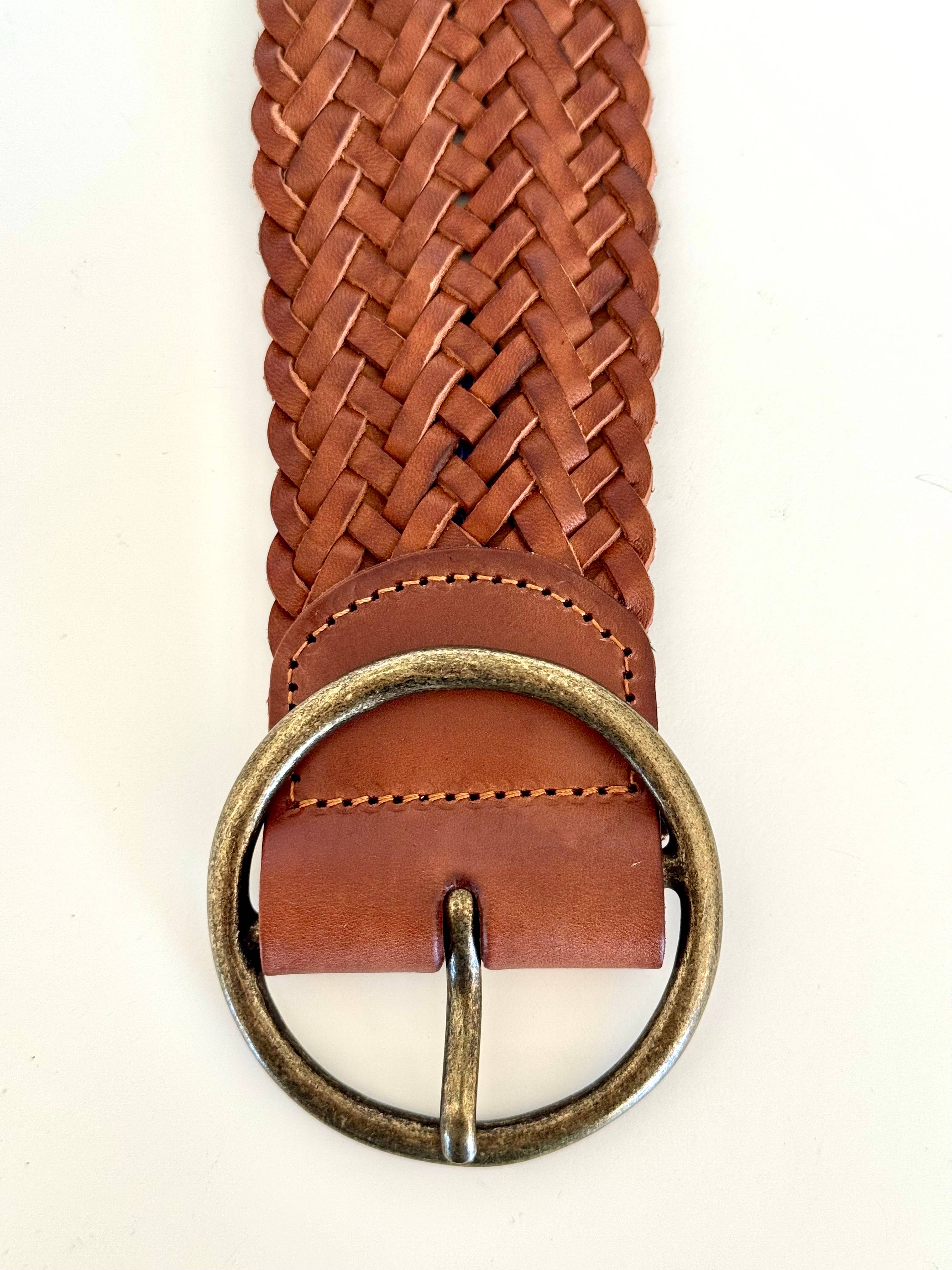 A close-up of the Ginger Blue Classic Wide Braided Leather Belt in Cognac, featuring a round antique brass buckle, displayed on a white background.