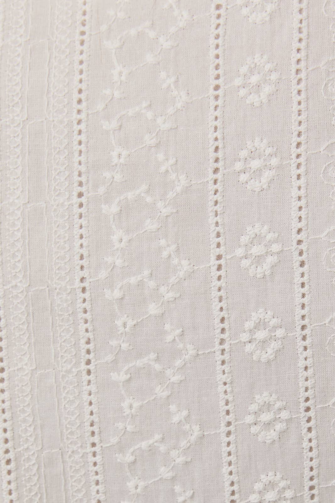 Close-up of white fabric with delicate embroidery detailing on Sleeveless Eyelet Mini Dress