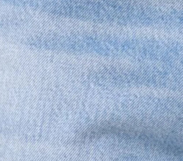 Close-up of soft light blue denim fabric texture for NYE SHORT in post with subtle woven detail and slight fading.