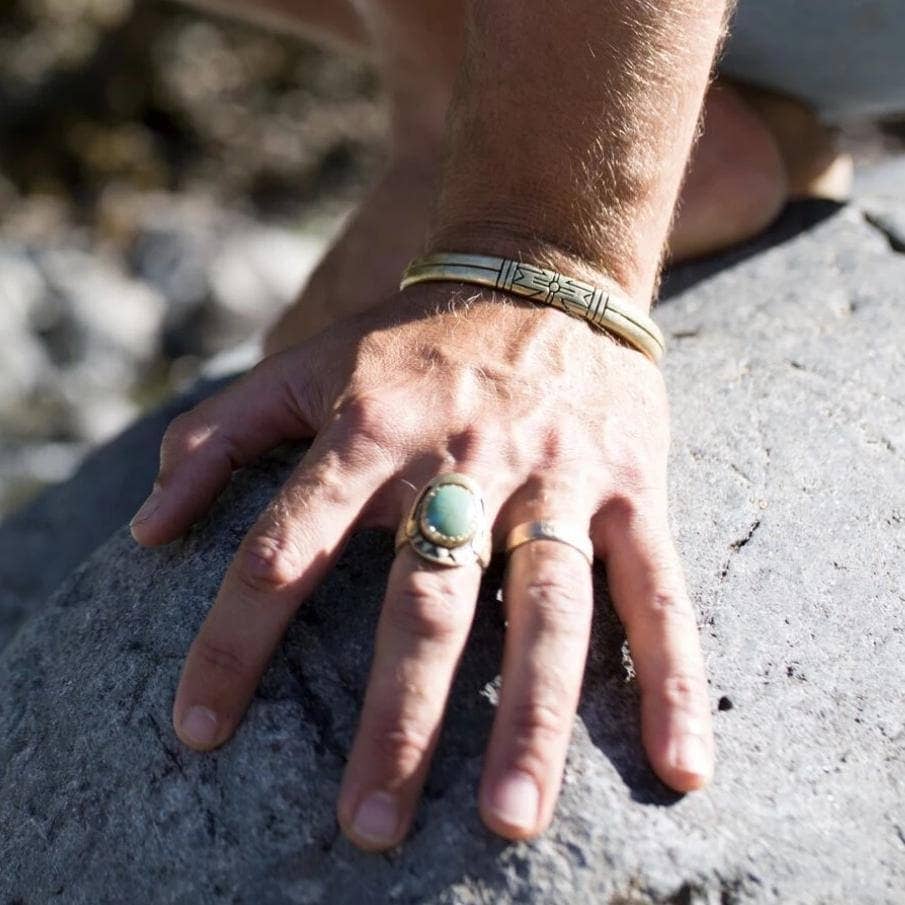 Man's hand resting on stone wearing Medicine Wheel Cuff || Men with silver and detailed engravings.