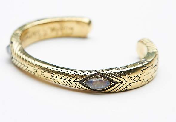 The Medicine Wheel Cuff by bahgsu jewels is a limited edition gold bracelet featuring engraved geometric patterns and a central marquise-shaped moonstone inlay, displayed against a white background.