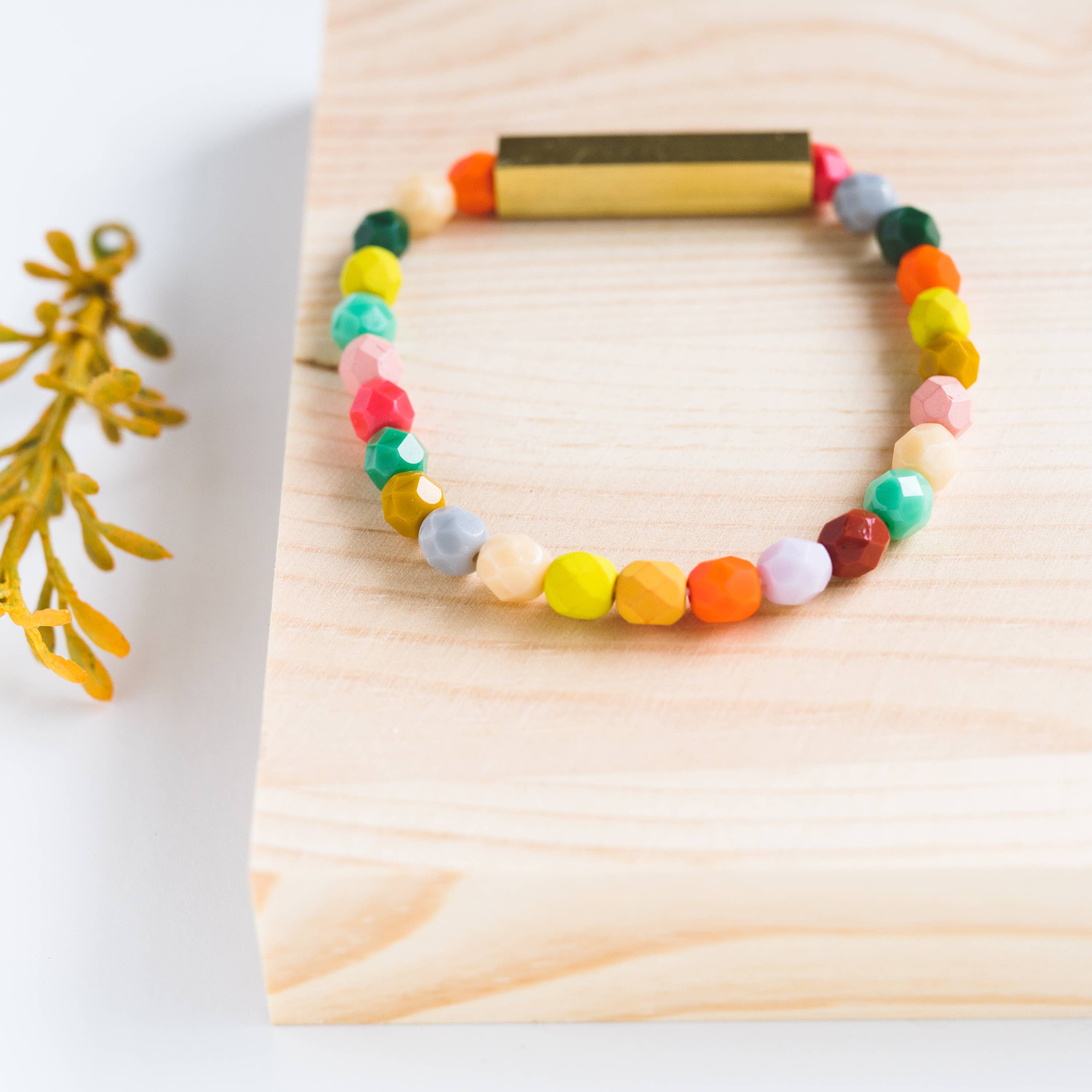 Colorful beaded bracelet on a wooden block with a white background