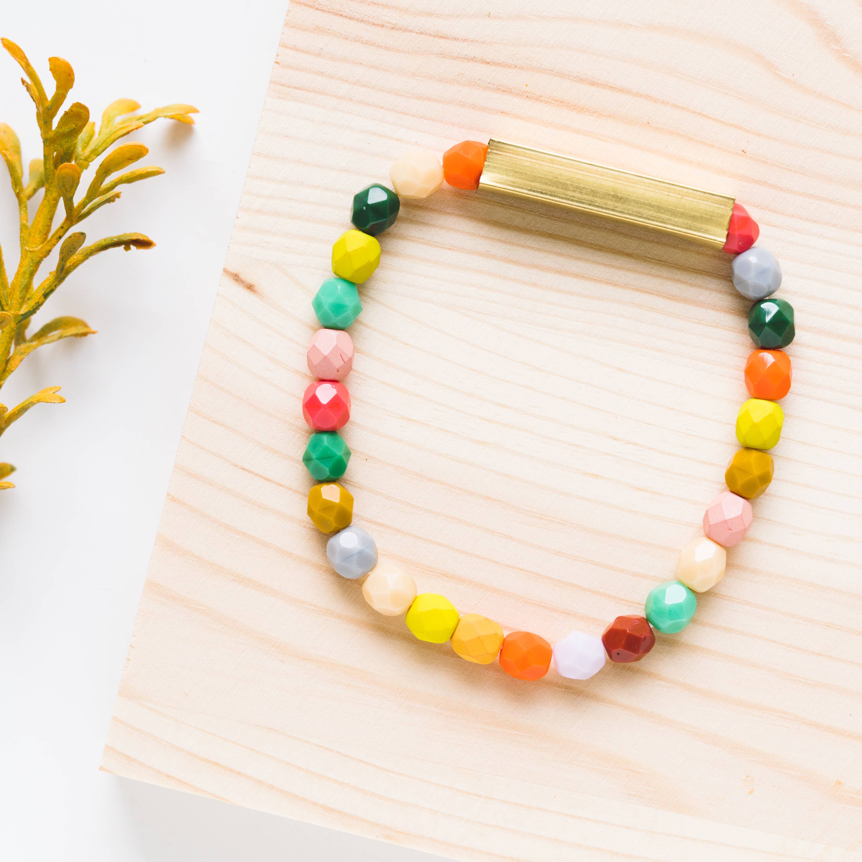 Mixed Beads and Brass Bracelet with colorful faceted beads and a sleek brass bar on light wood background