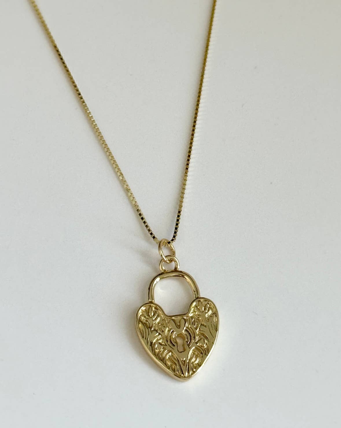 The Since Ive Been Loving You Necklace by Tramps+Thieves features a gold vermeil fine chain with a heart-shaped padlock charm engraved with floral details, shown against a plain white background.