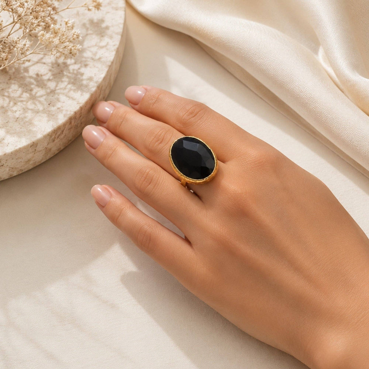 Oval Gold and Onyx Ring (Small) shown on a hand with a polished black oval stone.