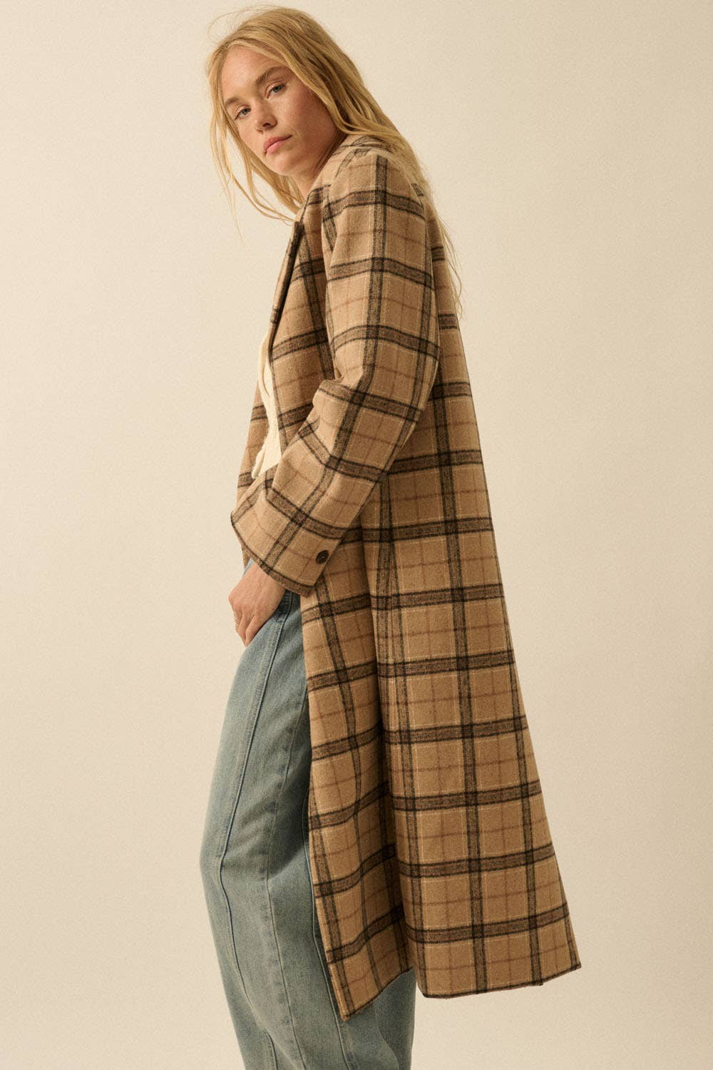 A woman with long blonde hair models the Promesa USA Plaid Felt Double-Breasted Calf-Length Overcoat over light blue jeans, standing sideways against a plain light background.