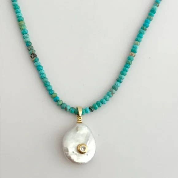 The Mar Turquezza Necklace by Tramps+Thieves features turquoise beads, a gold-accented pendant with an irregular white baroque pearl and a small gemstone set in gold, finished with a secure gold-filled clasp.