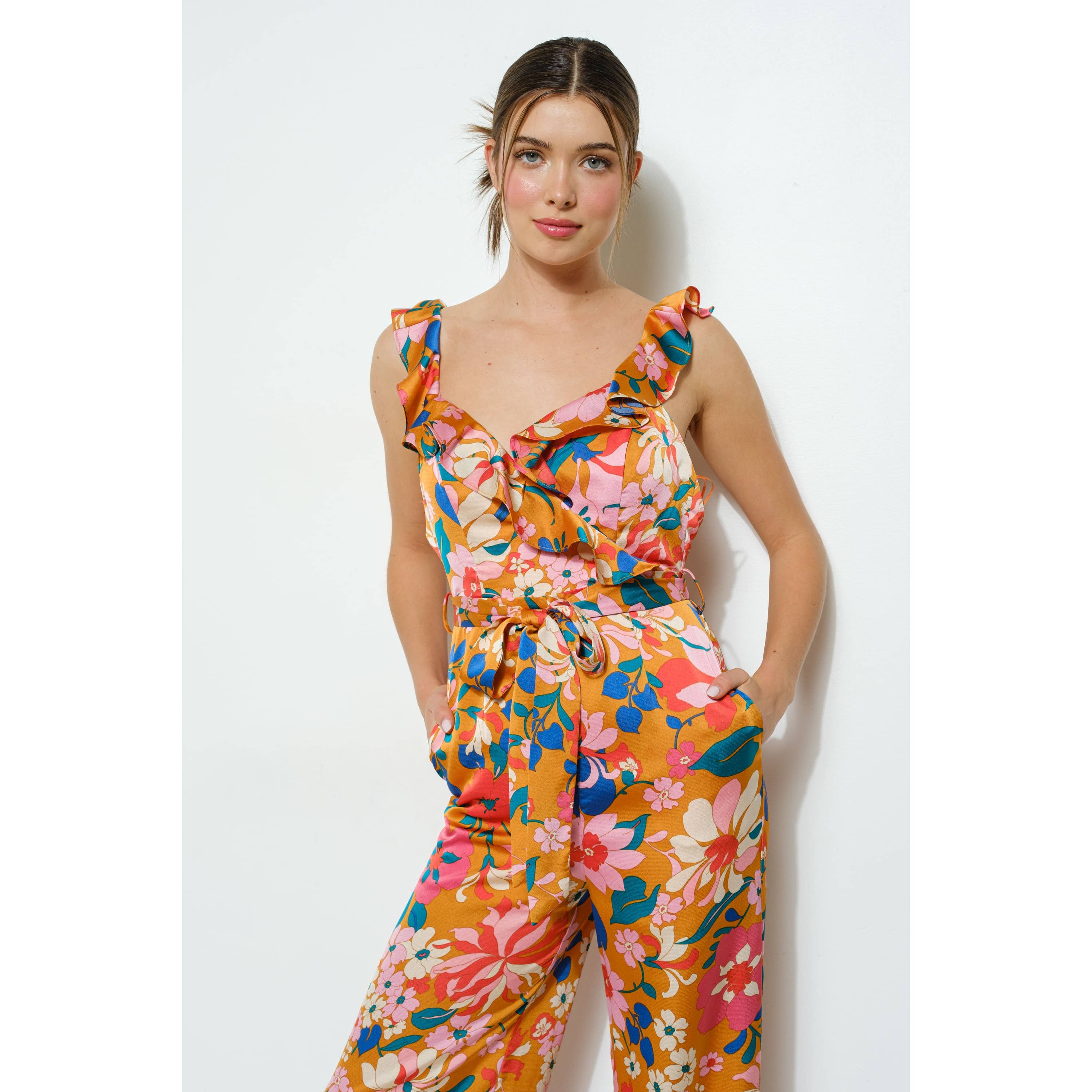 Woman wearing a colorful floral jumpsuit against a white background