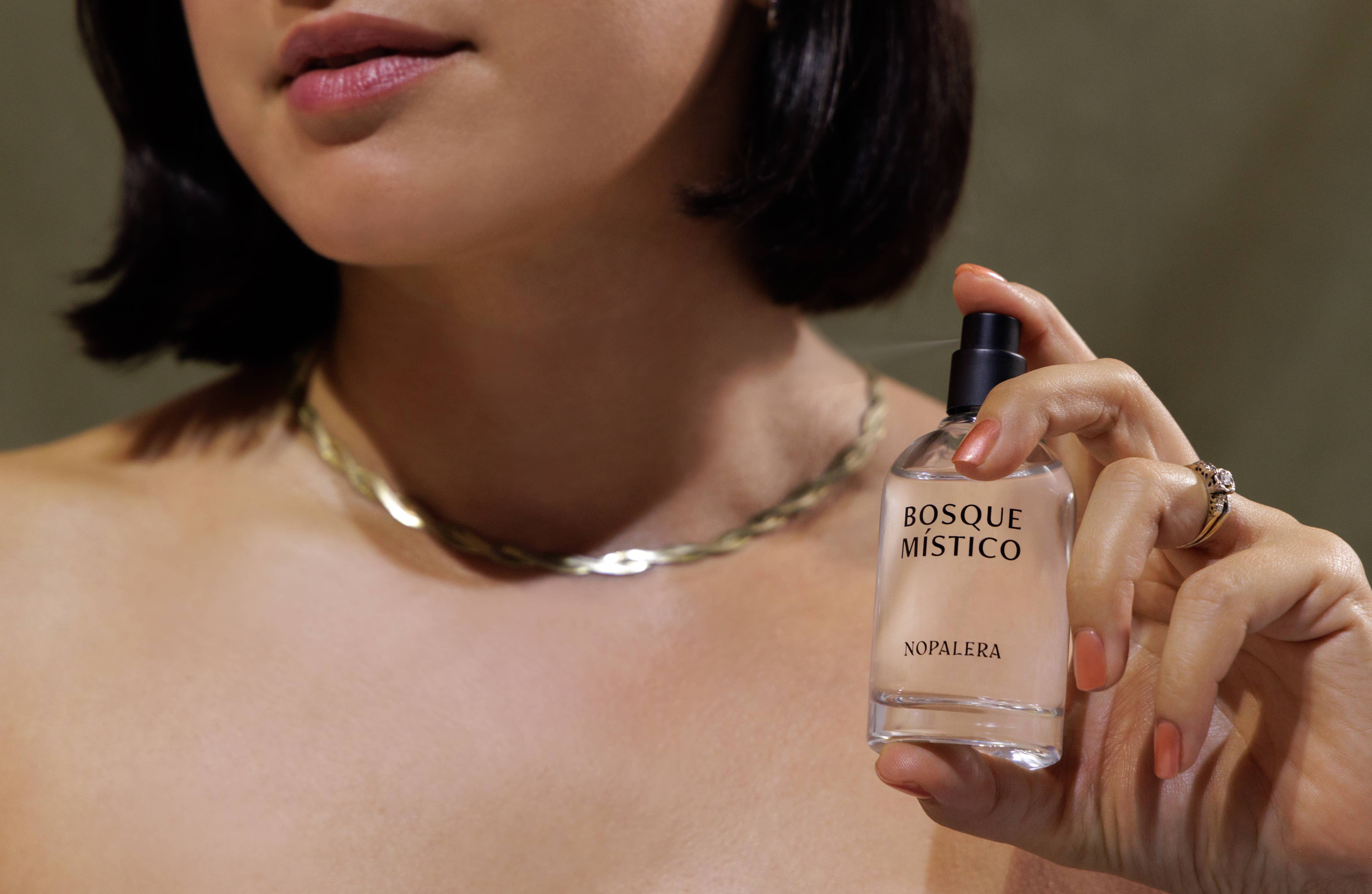 A woman with short dark hair holds a Nopalera Bosque Místico Eau de Parfum 10mL Travel Spray—her peach nails and gold jewelry evoking the essence of Mexico’s mystical forests in this clean, travel-friendly fragrance.