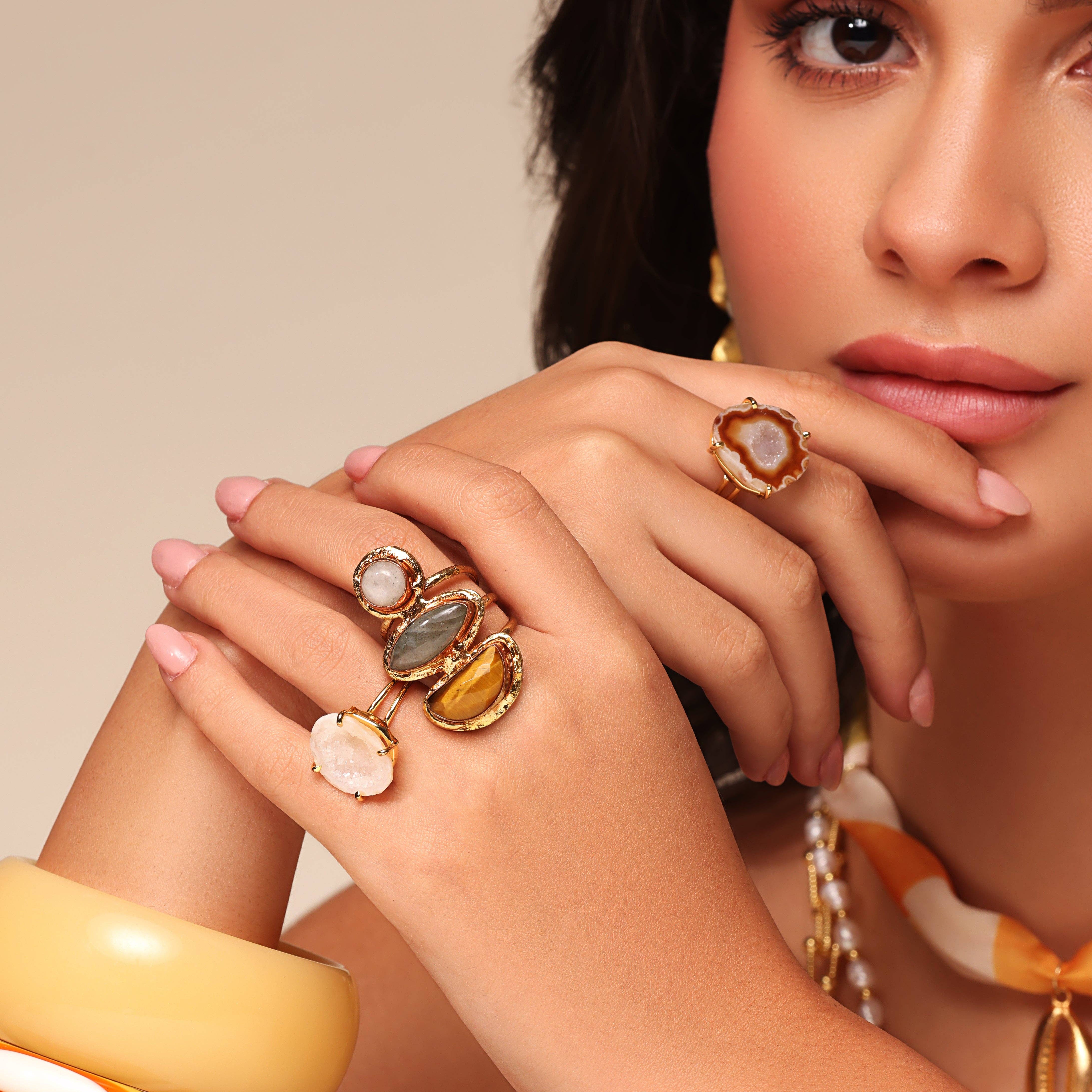 Close-up of a woman wearing colorful gemstone Cocktail Rings on her fingers with a polished gold setting