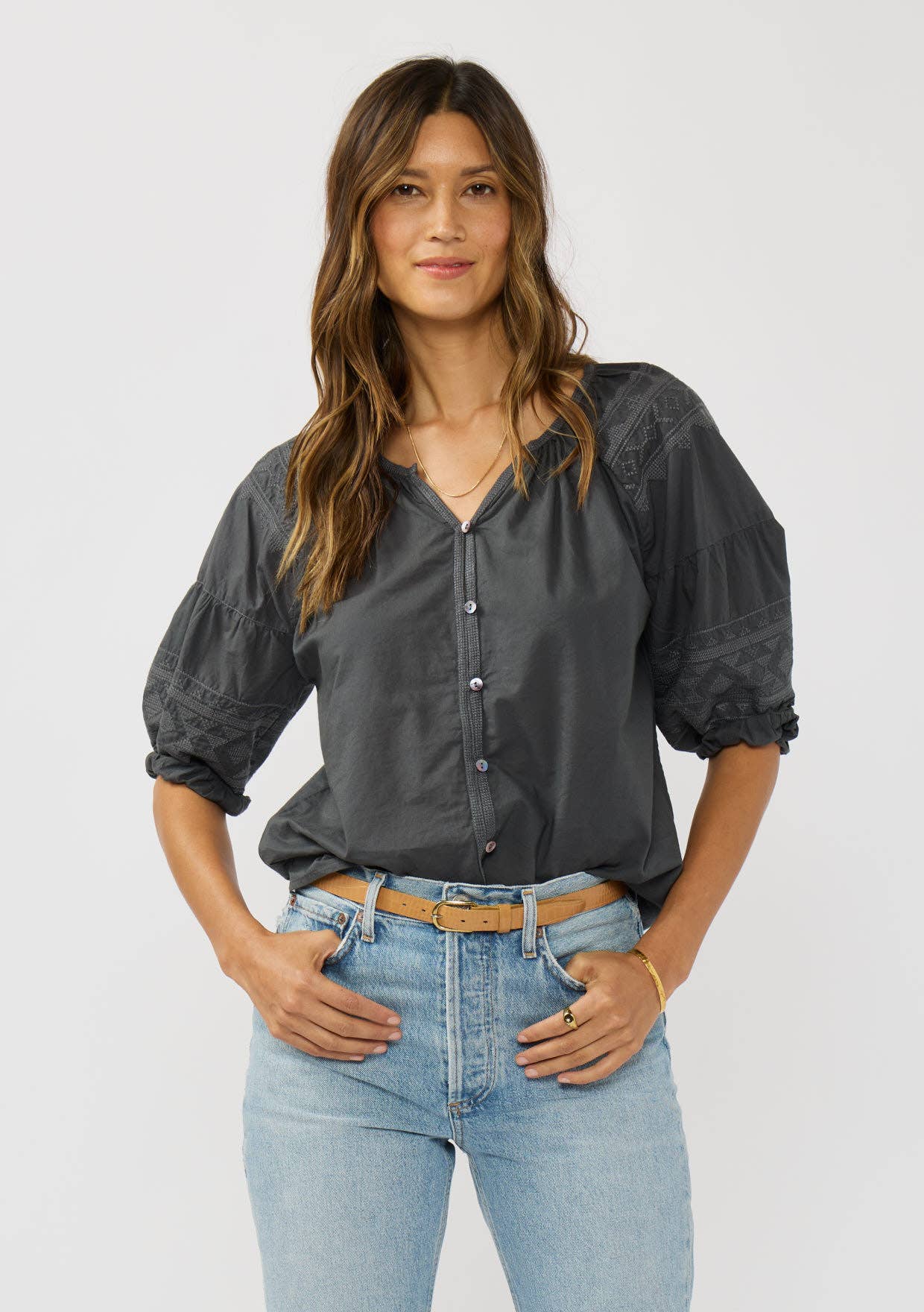 Woman wearing a charcoal Short Raglan Puff Sleeve Button Down Top paired with light blue jeans and a tan belt.
