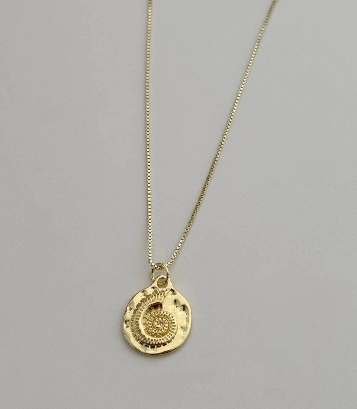 The Mar Medallion Necklace by Tramps+Thieves features a gold vermeil, round shell pendant with spiral and dot patterns, shown on a simple light gray background.