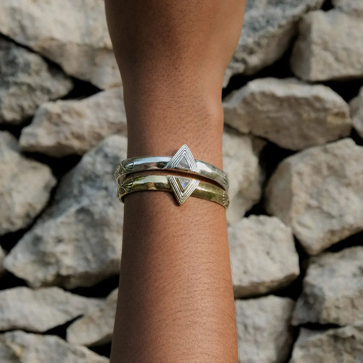Hold Space Cuff featuring mixed metal design with textured brass and silver bands on wrist against stone background