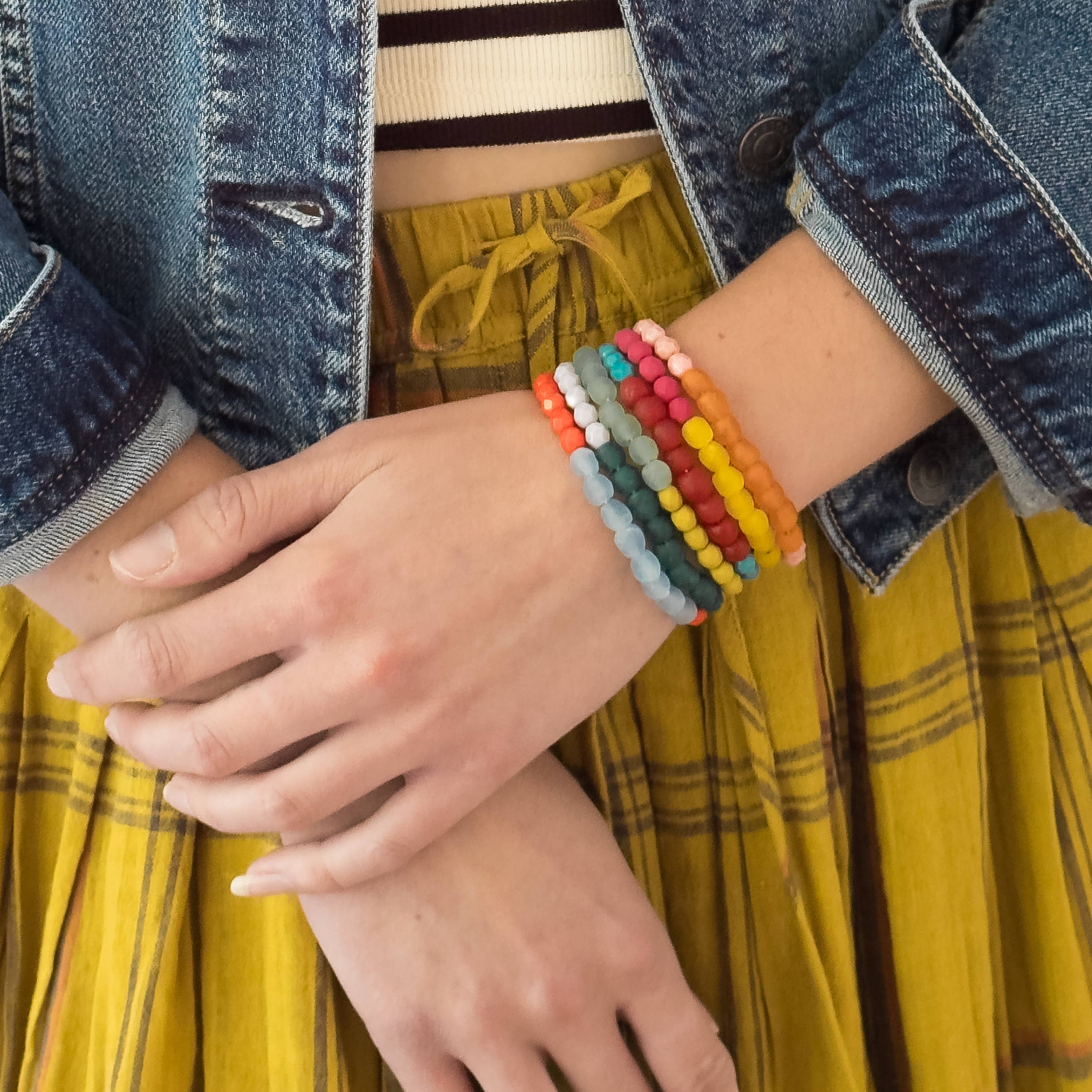 Close-up of a person wearing a Multicolor Recycled African Glass And Mixed Bead Bracelet layered with casual clothing style