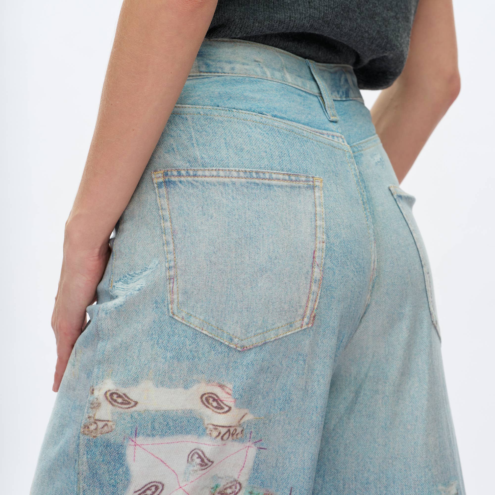 Close-up of BAYEAS Light Blue Patch Pattern High-Rise Barrel Jeans, featuring artistic patches near the left pocket. The focus is on the back and side, highlighting the comfort stretch denim.