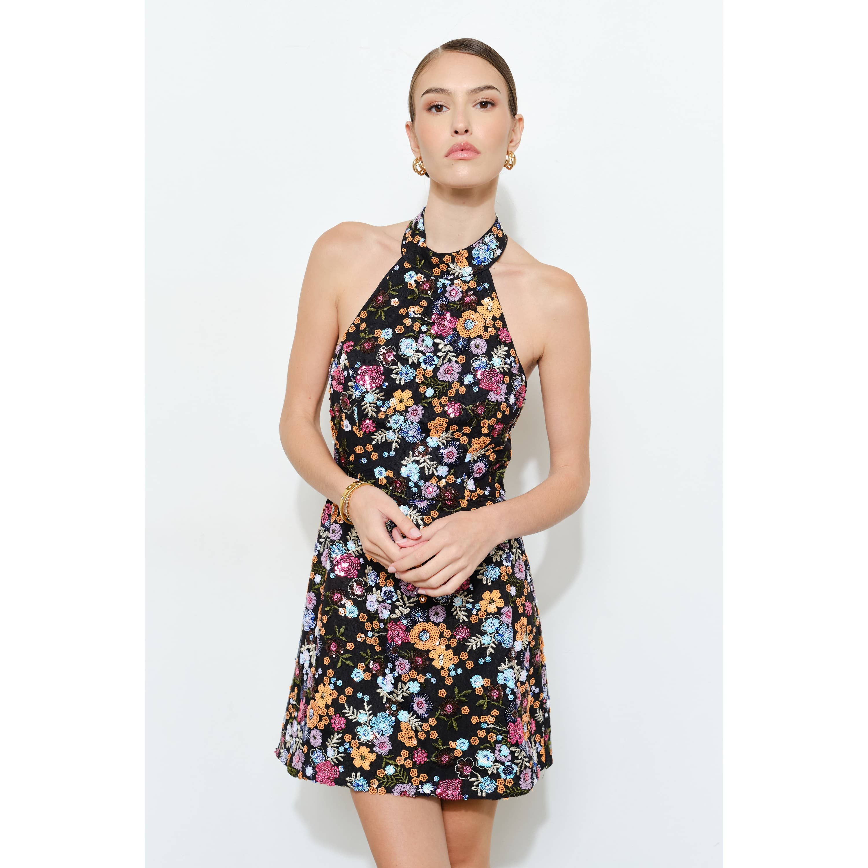 Woman wearing a Floral Sequins Embellished Halter Neck Mini Dress with colorful floral patterns on black fabric