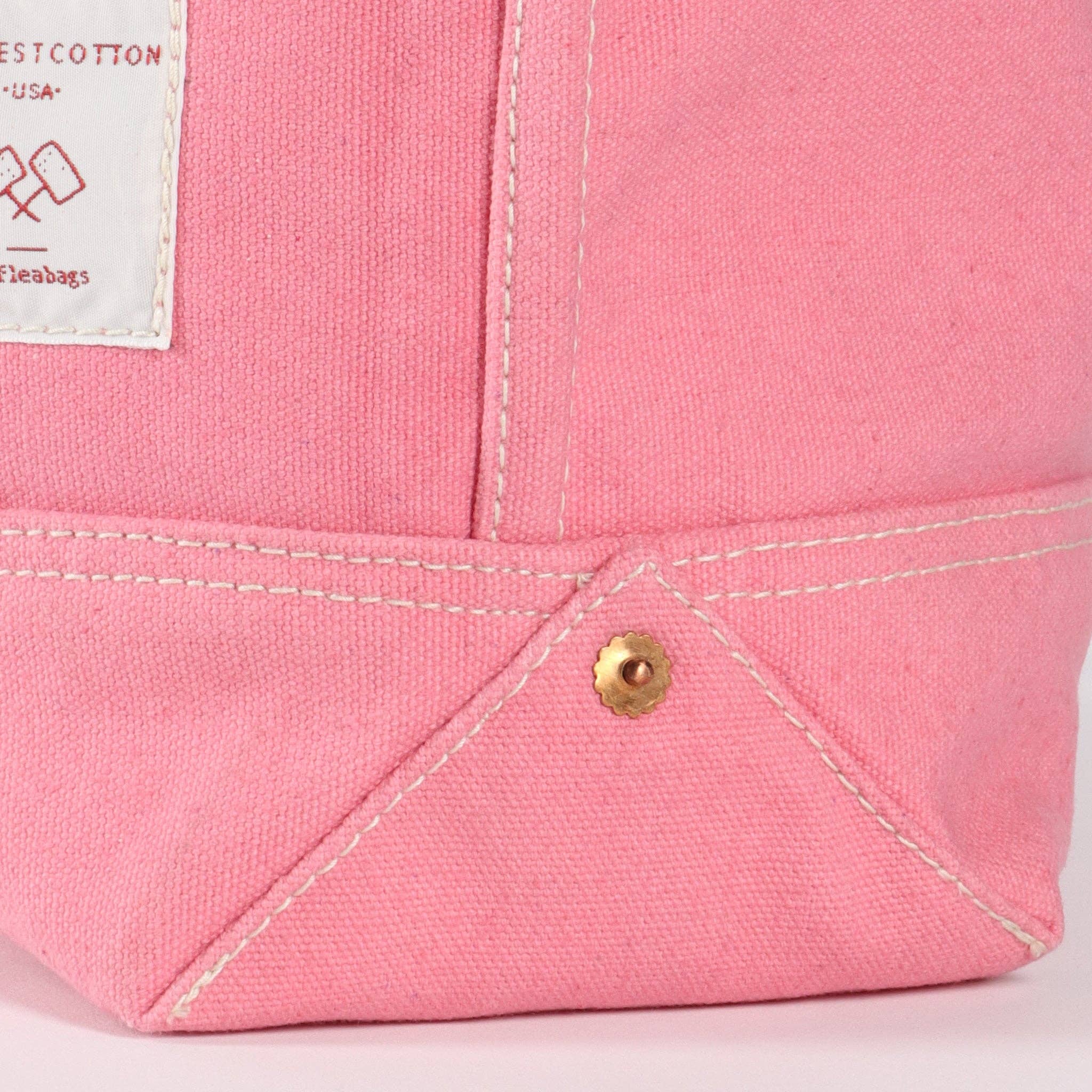 Close-up of pink canvas fabric detail with white stitching and brass rivet on Small East West Tote | Flamingo