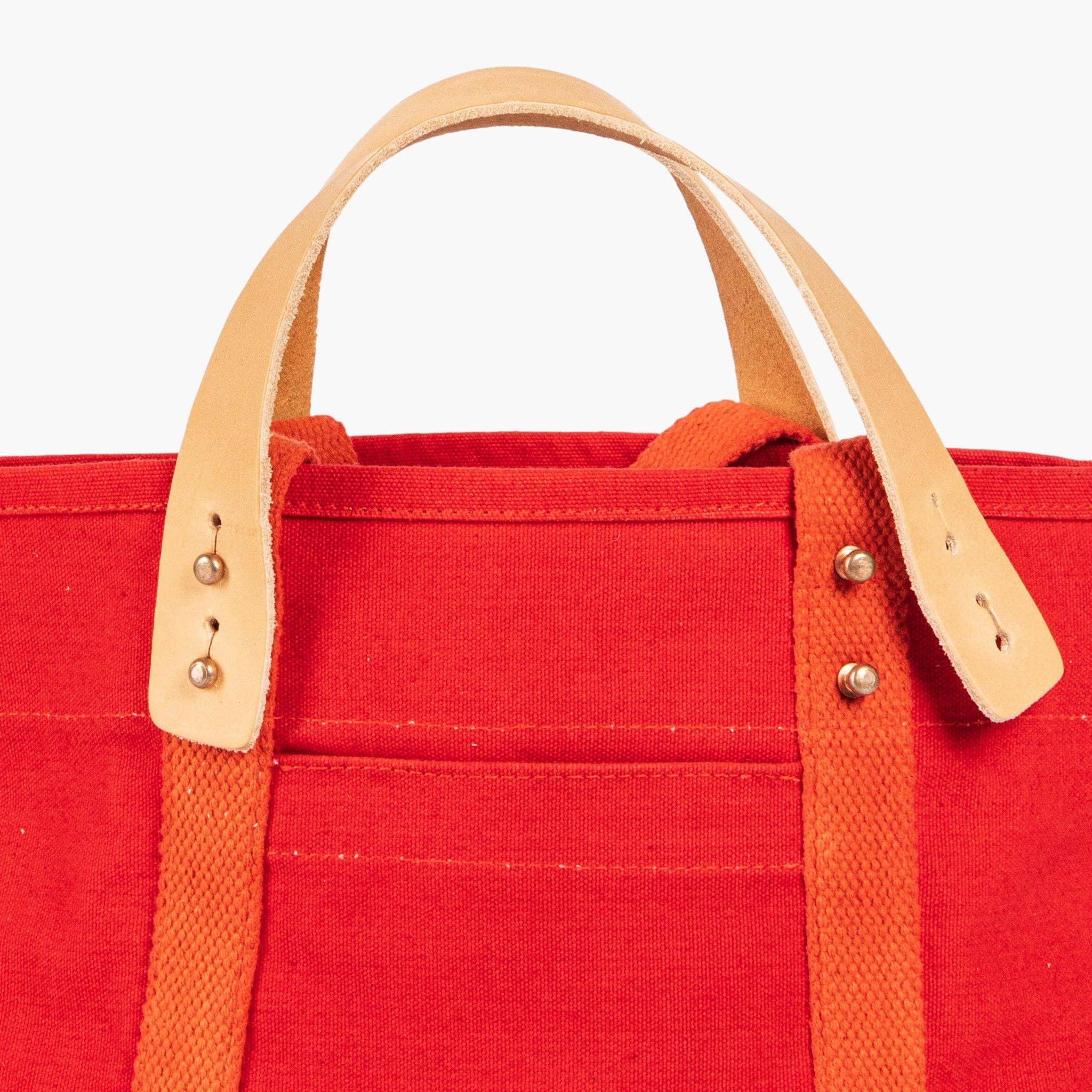 Close-up of Lunch Tote | Persimmon in vibrant fabric with tan leather handles and brass rivet details.