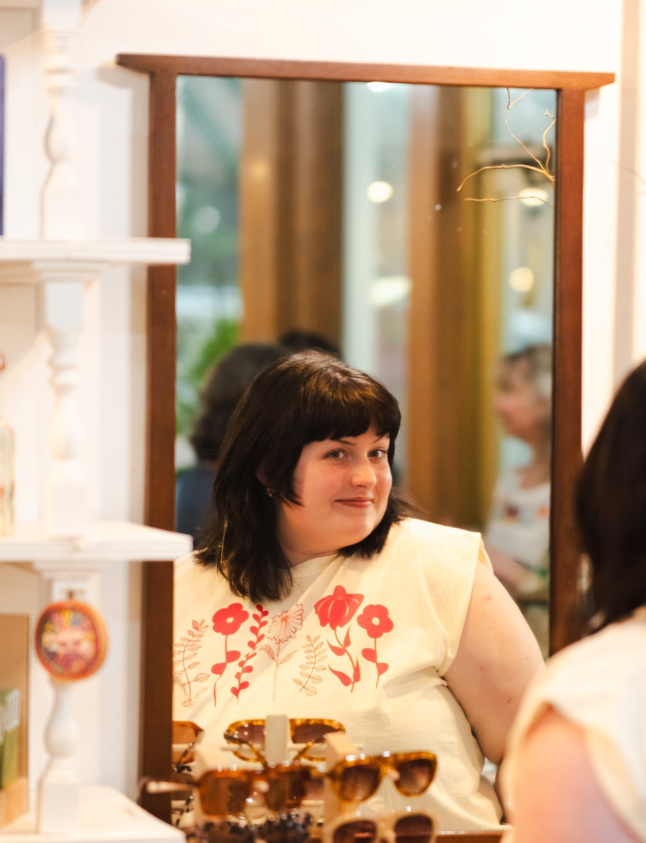 Woman looking at sunglasses in a store mirror