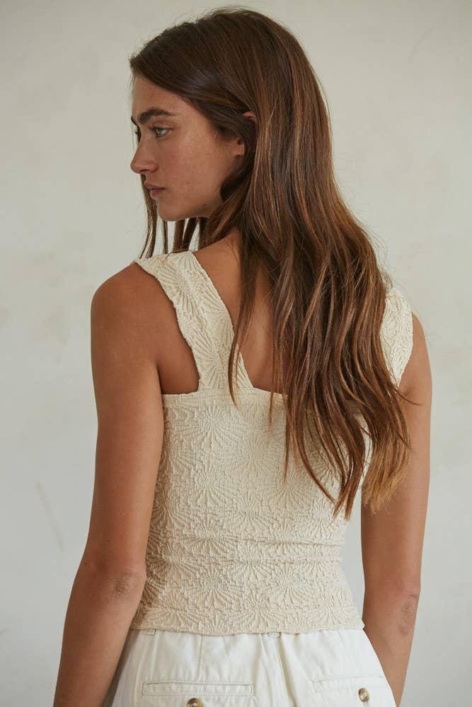 A woman with long brown hair stands with her back to the camera in a By Together Knit Modal Nylon Spandex Seamless Jacquard Tank and white bottoms, set against a plain, light-colored background.