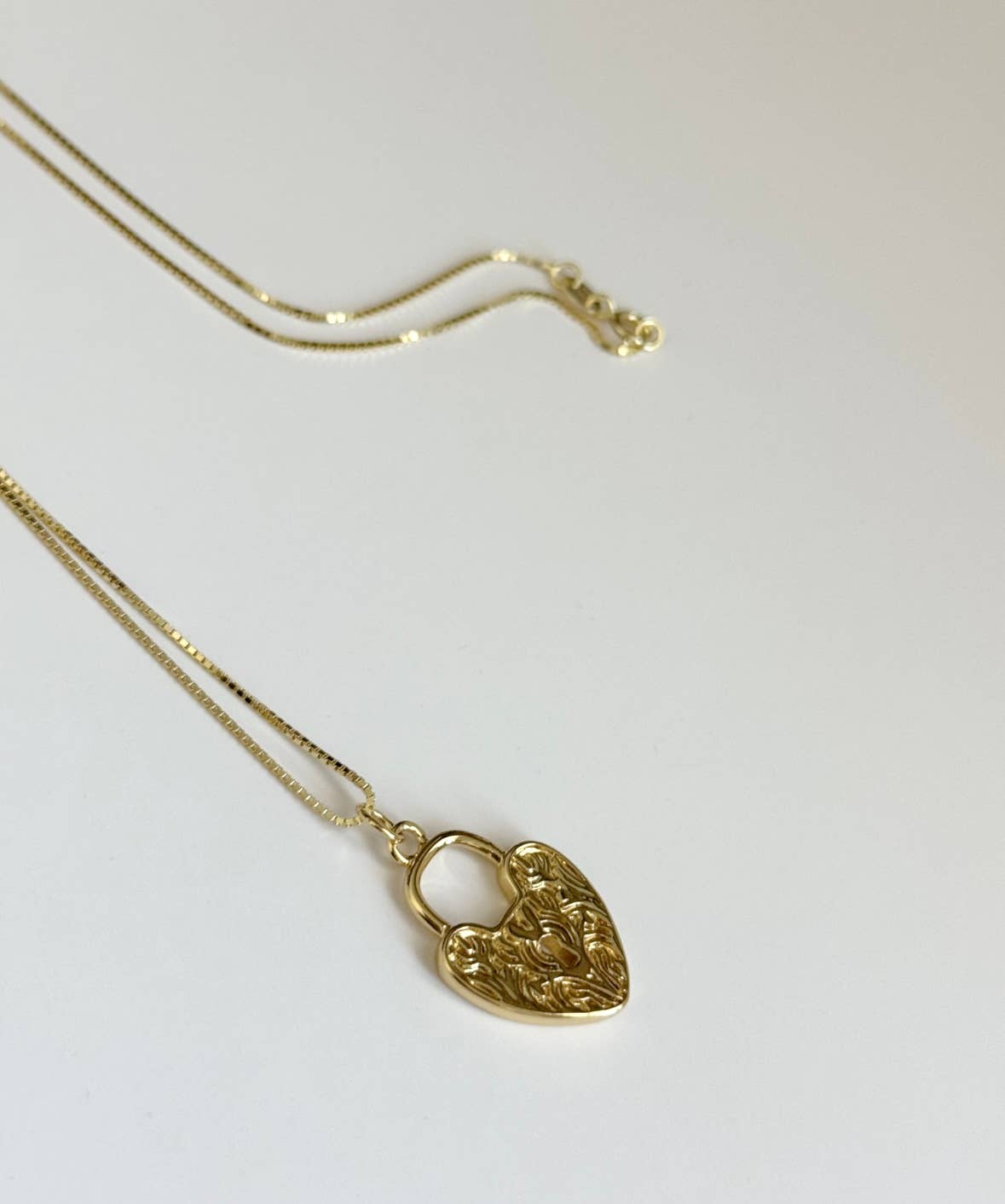 The Since Ive Been Loving You Necklace by Tramps+Thieves features a gold vermeil chain and heart lock charm with intricate floral engravings, shown on a plain white background.
