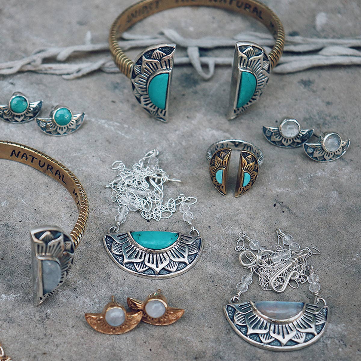 Discover the Natural Mystic Ring - Turquoise by bahgsu jewels, a boho-style sterling silver ring with turquoise, displayed alongside gold earrings, bracelets, and necklaces on a textured stone surface.