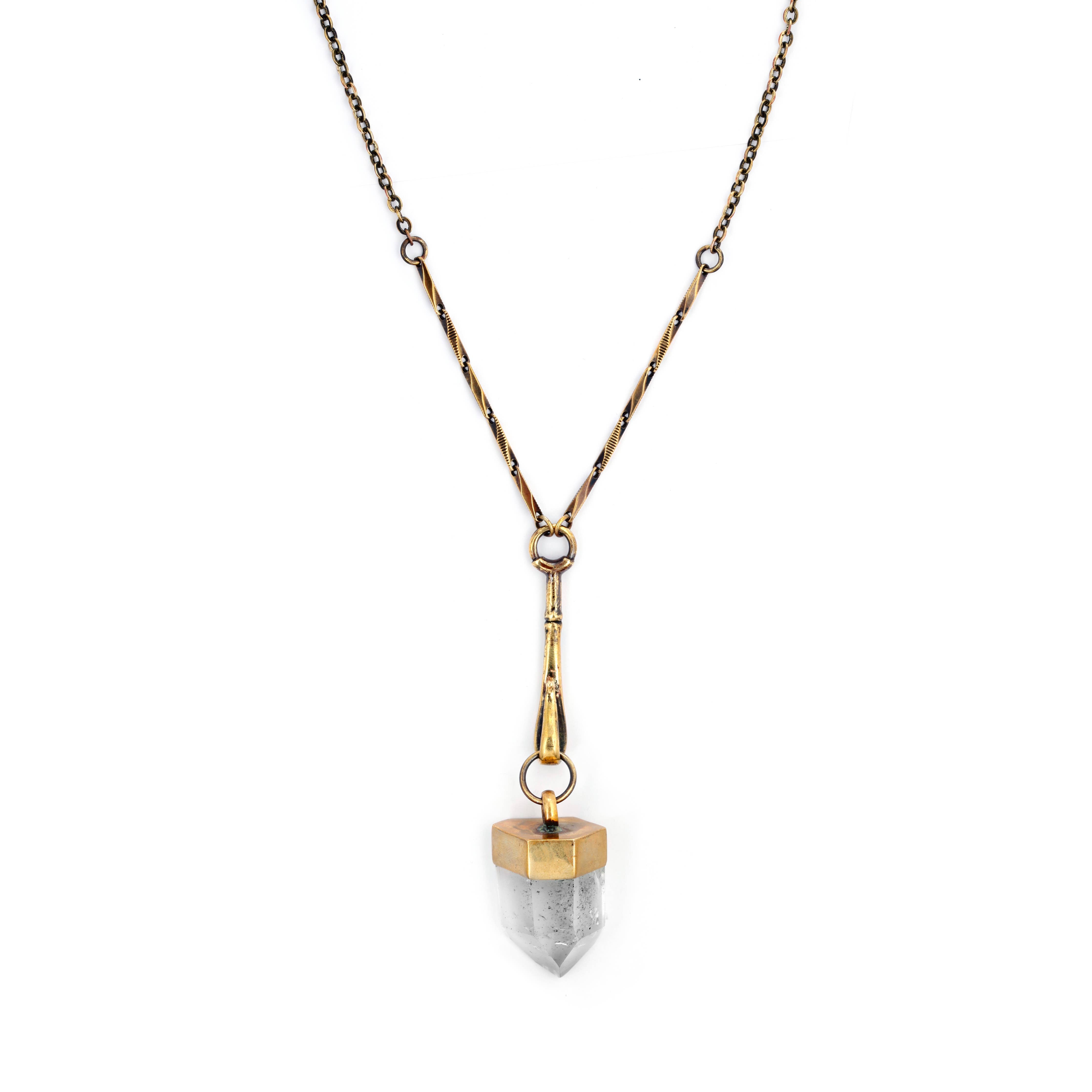 The Jan Hilmer + Sparrow Crystal Pendulum Necklace Brass features a geometric, double-pointed quartz pendant with gold caps and decorative gold bar accents on each side of the chain.