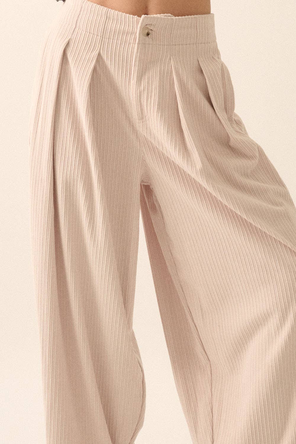 Close-up of Promesa USA Velvet Corduroy Pleat-Front Wide-Leg Pants in beige, featuring a ribbed texture, high waist, relaxed fit, and button-zipper closure. Photo is cropped below the waist with a light background.