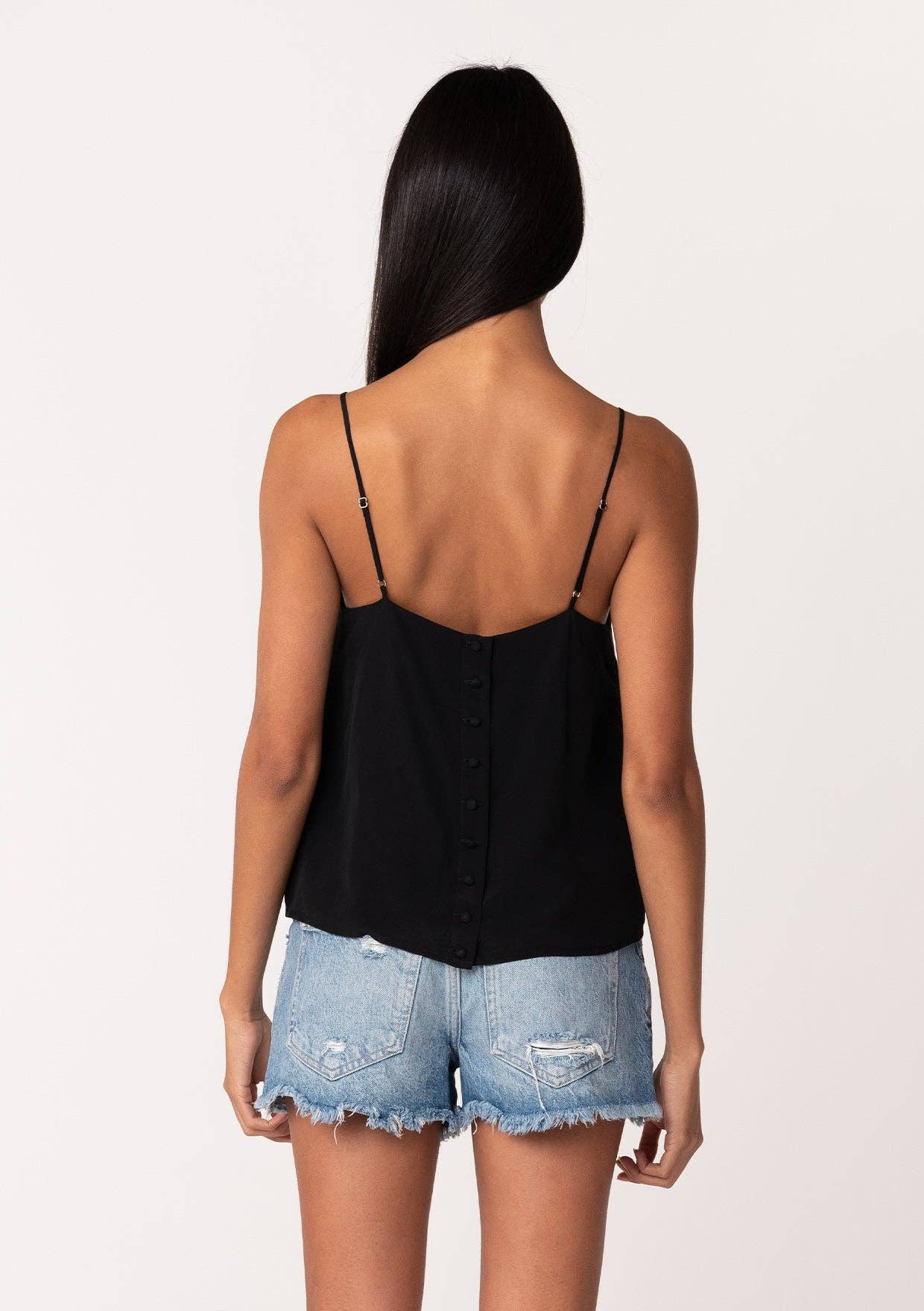 Woman wearing black Button Back Embroidered Lace Cami with thin straps paired with denim shorts, shown from back view