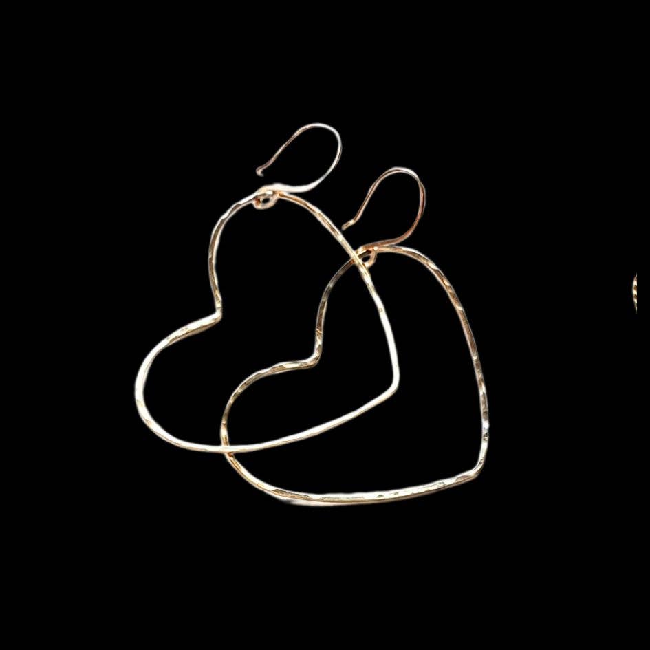 The Big Gold Heart Hoop Earrings by Dreamers of Dreams are displayed on a solid black background, highlighting their bold and charming statement design.