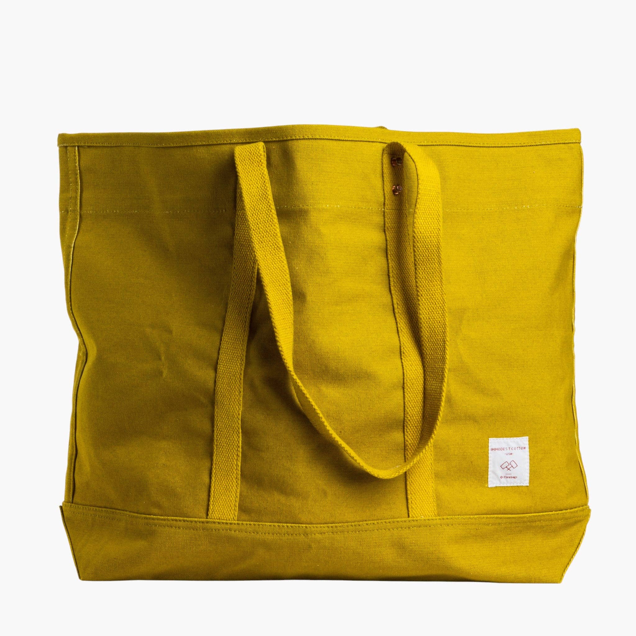 Yellow tote bag with a small white label on a white background