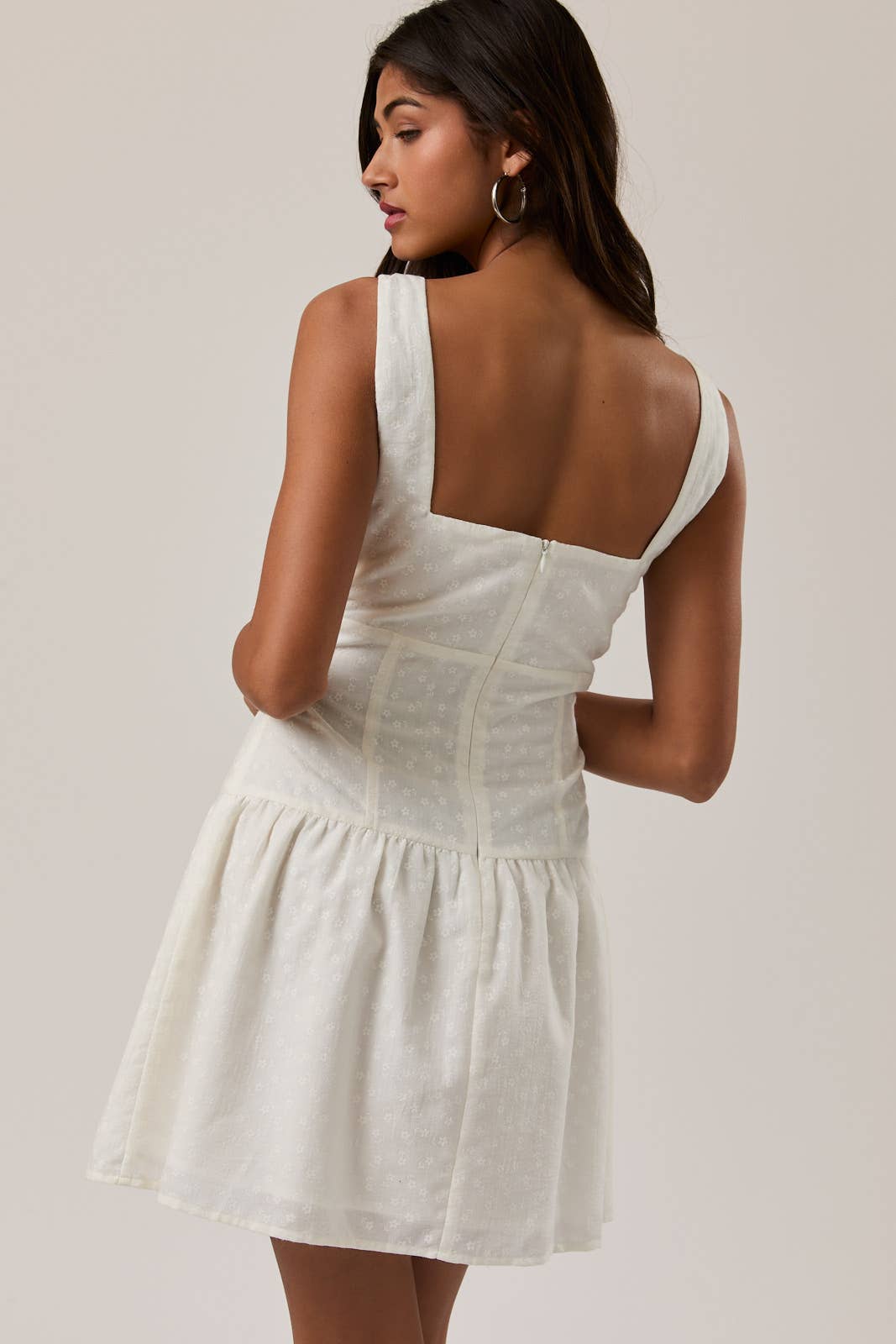 Woman wearing a white Shirred Neck Low Waist Mini Dress with wide straps and back zipper detailing