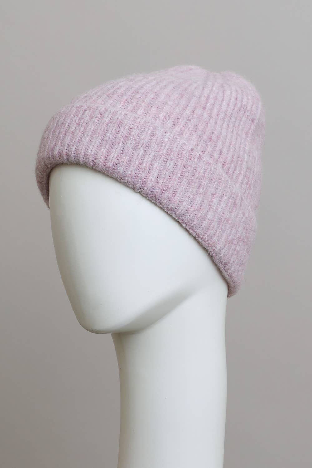 The Versatile Cuffed Beanie by Leto Accessories, shown in pale pink with a rib knit and folded brim, sits on a white mannequin head against a light gray background—its soft texture makes it ideal for fall.