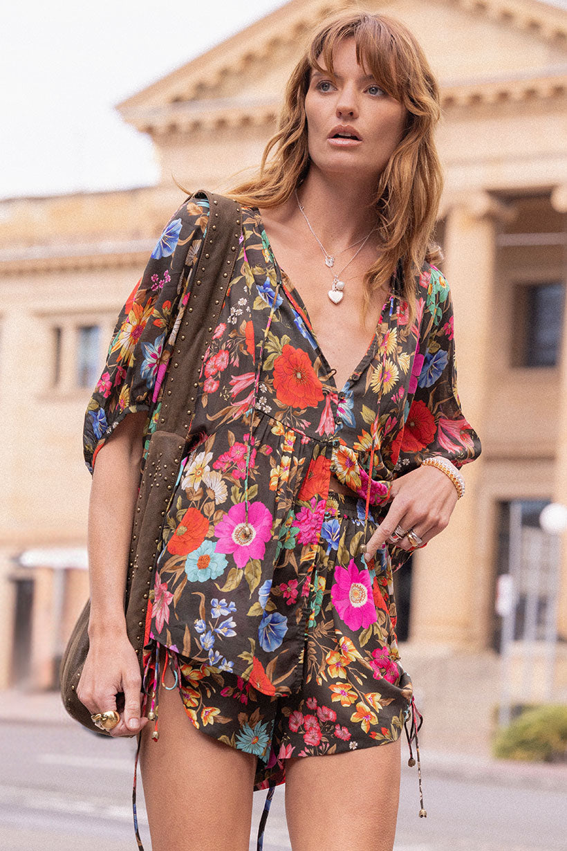 Woman wearing Valley of the Dolls Boho Blouse with colorful floral print and relaxed bohemian style outdoors.
