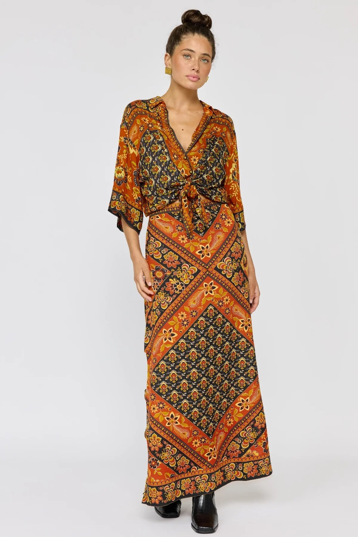 Woman wearing Whitney Skirt in Saffron with bohemian floral patterns and warm earthy tones styled with a matching top.