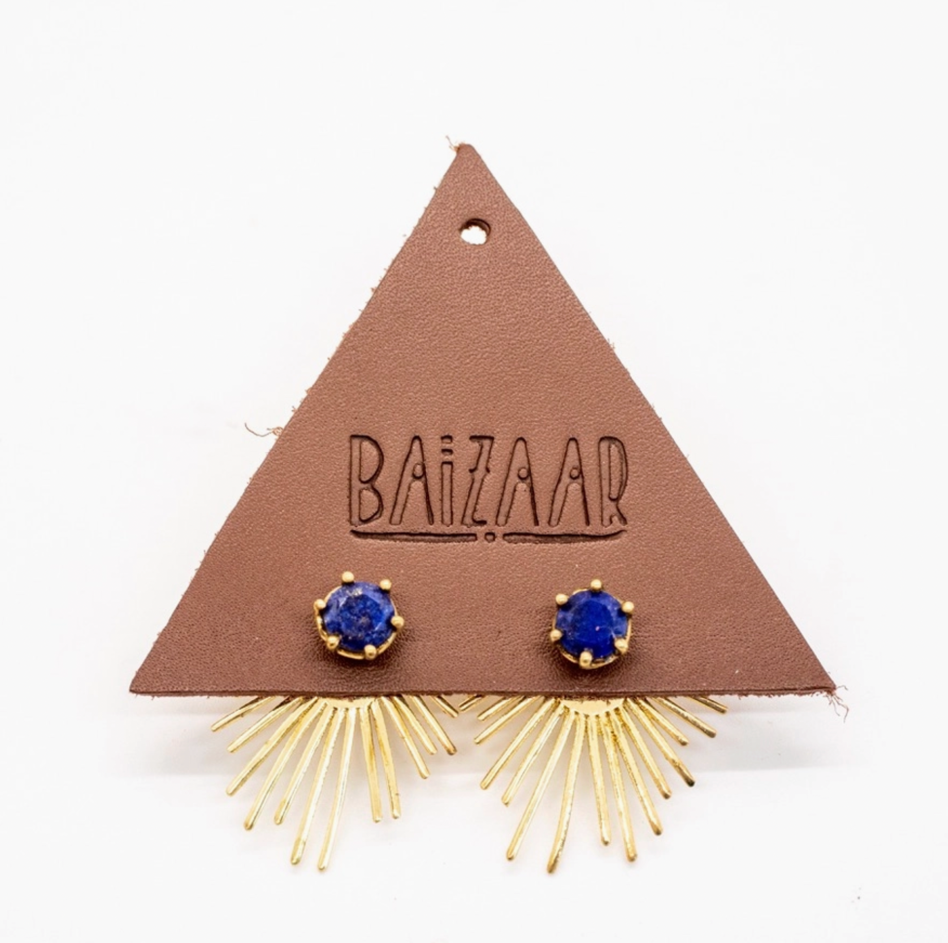 The Brass Starburst Ear Jacket in Lapis by Baizaar features faceted lapis studs and sunburst-shaped brass rays, displayed on a brown triangular card. This handmade pair captures the elegance of a striking, star-inspired design.