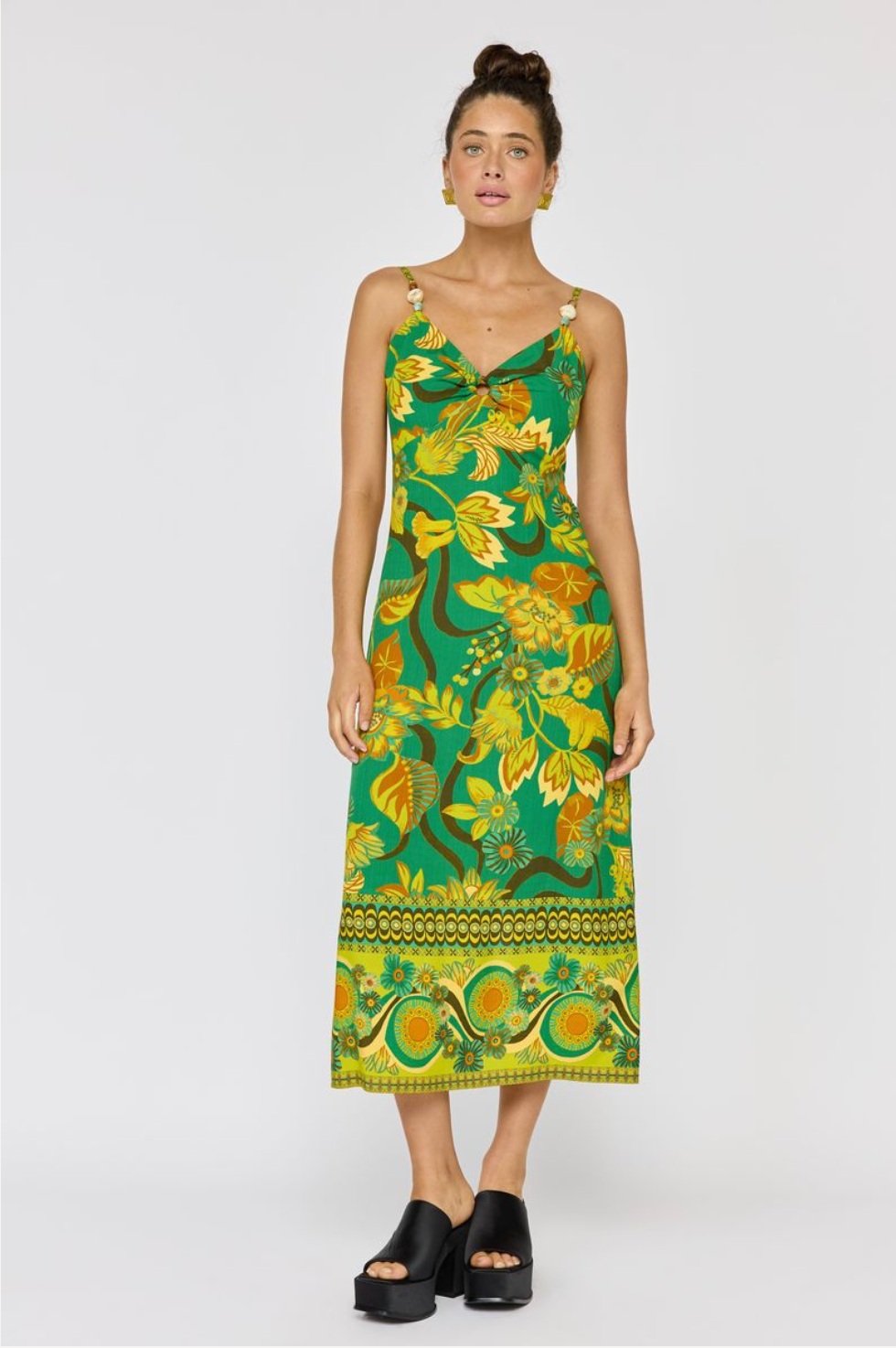 Woman wearing a vibrant green patterned Martini Midi Dress in Absinthe with floral and abstract designs and beaded straps