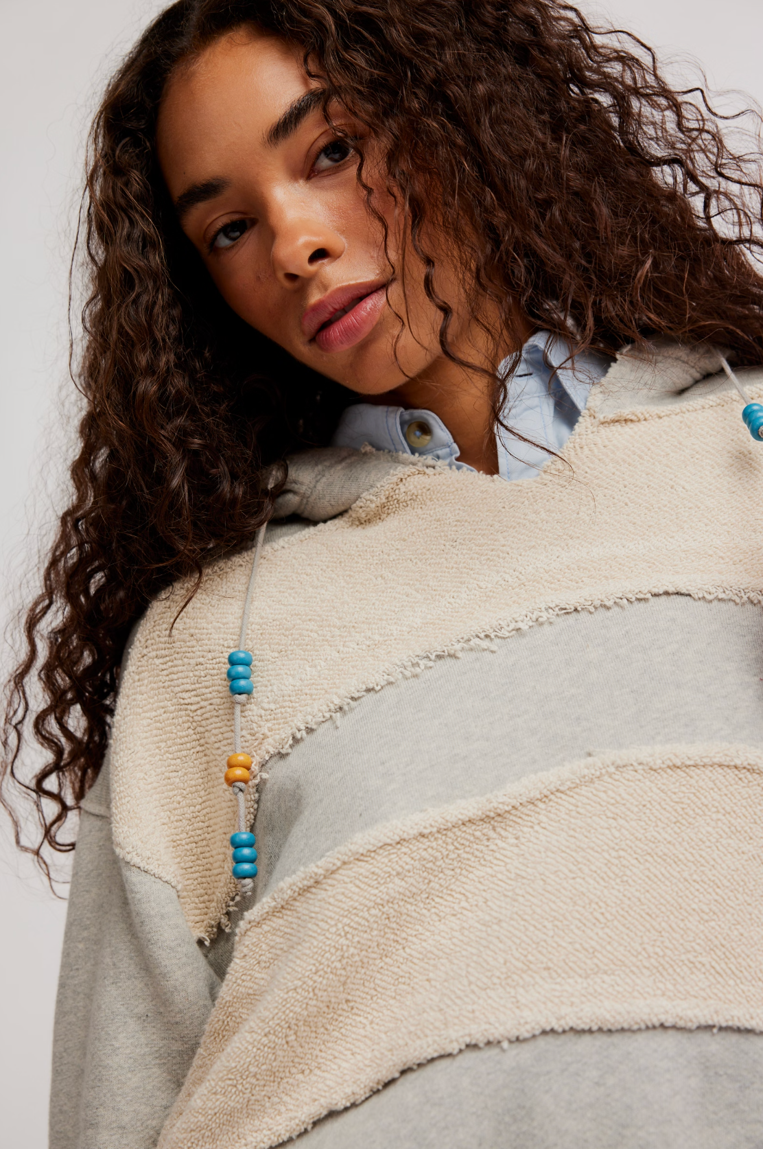 Close-up of a woman wearing a cozy Camp Crush Hoodie with textured fabric and colorful bead details on the drawstrings.