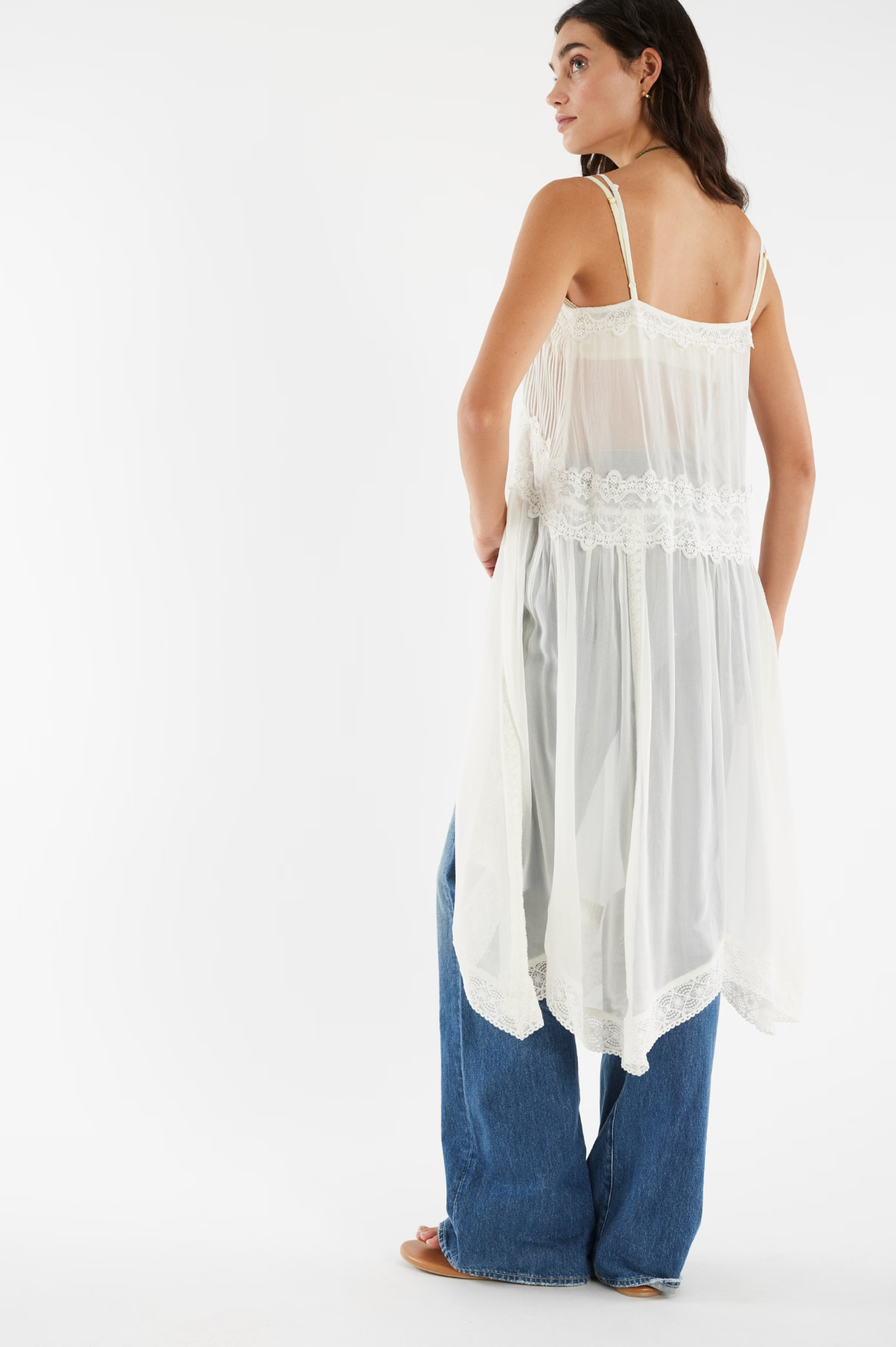 Woman wearing a flowing, sheer Snowbird Maxi Top with lace details layered over blue wide-leg jeans.