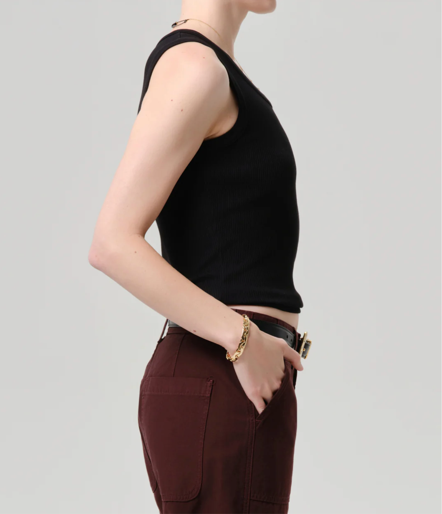 Side profile of a model wearing The Nova Tank by Citizens of Humanity in Black styled with brown pants and gold bracelet