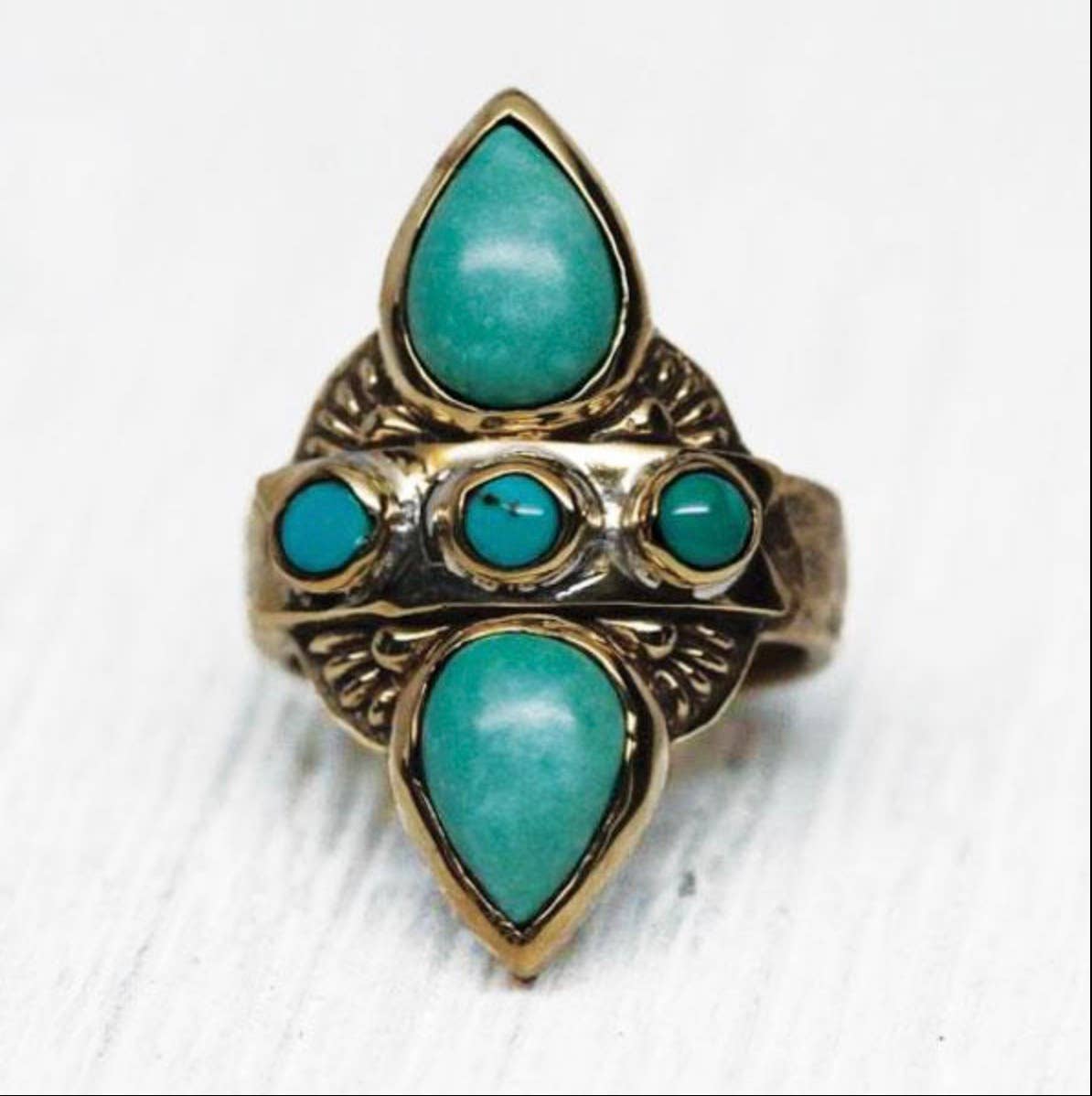 The Truth Seeker Ring by bahgsu jewels features yin yang vibes with two large teardrop turquoise stones and three small round center stones, elegantly displayed on a white surface.