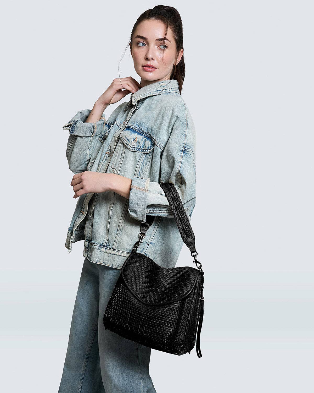 Woman modeling All For Love Novelty Zip Top Convertible Shoulder bag in black with woven texture and casual denim outfit