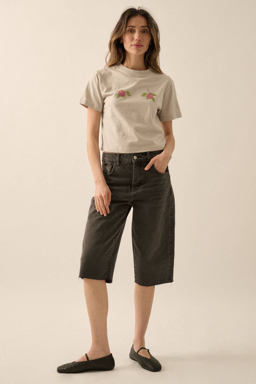 Woman wearing Cherries Cropped Garment-Dyed Graphic Tee with black mid-length denim shorts and flat shoes