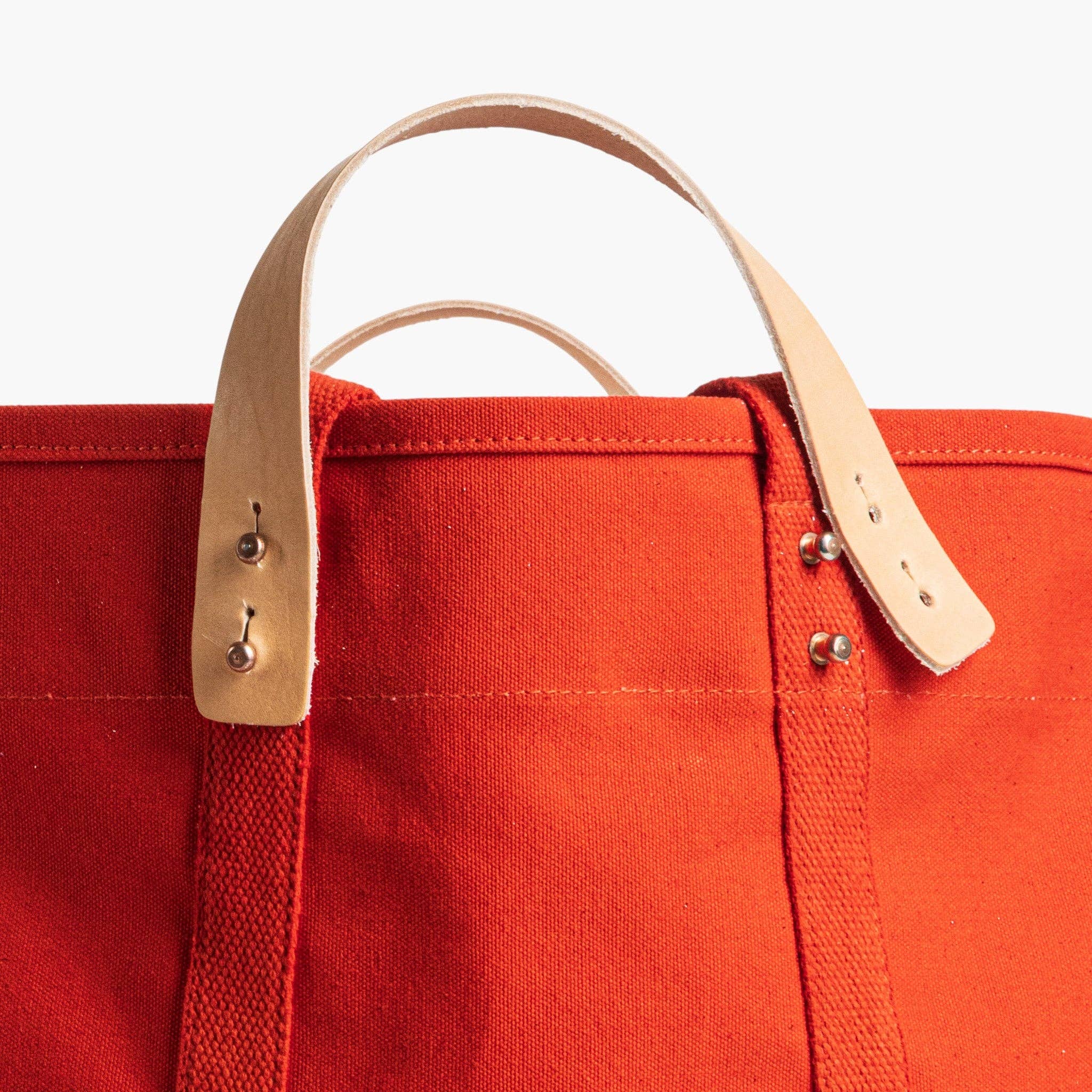 Close-up of leather handles and reinforced stitching on a bright Large East West Tote | Persimmon canvas bag