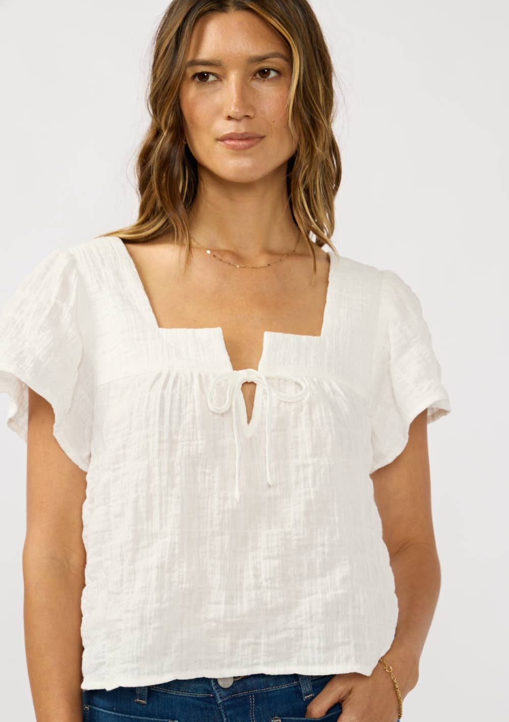 Woman wearing a white Square Neck Puff Sleeve Gauze Top with delicate texture and short flutter sleeves.