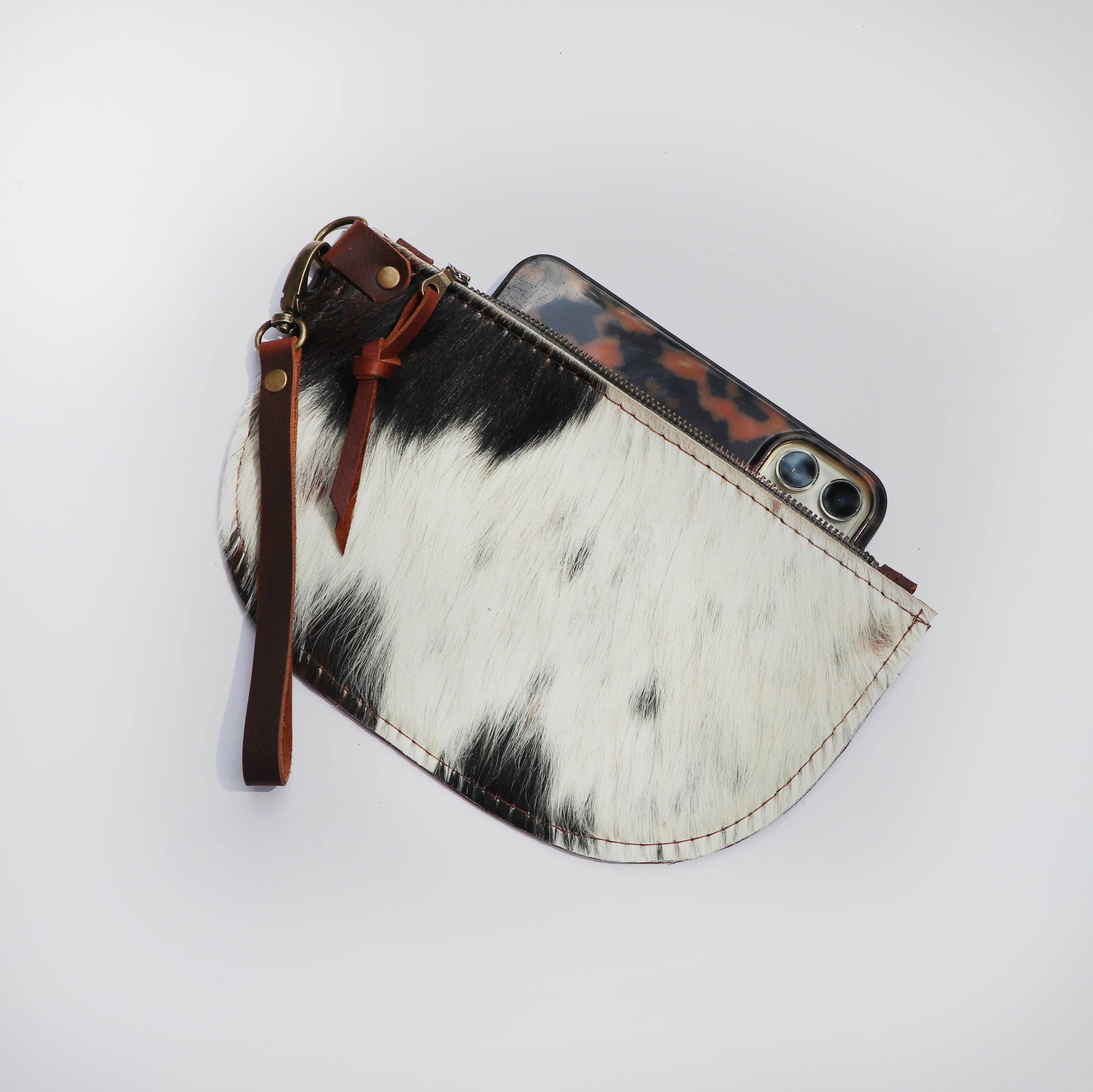 The Hawks & Doves Large Half Moon Cowhide and Leather Zip Pouch with Wristlet, shown partially unzipped to display a smartphone in a tortoiseshell case inside, is set against a white background.