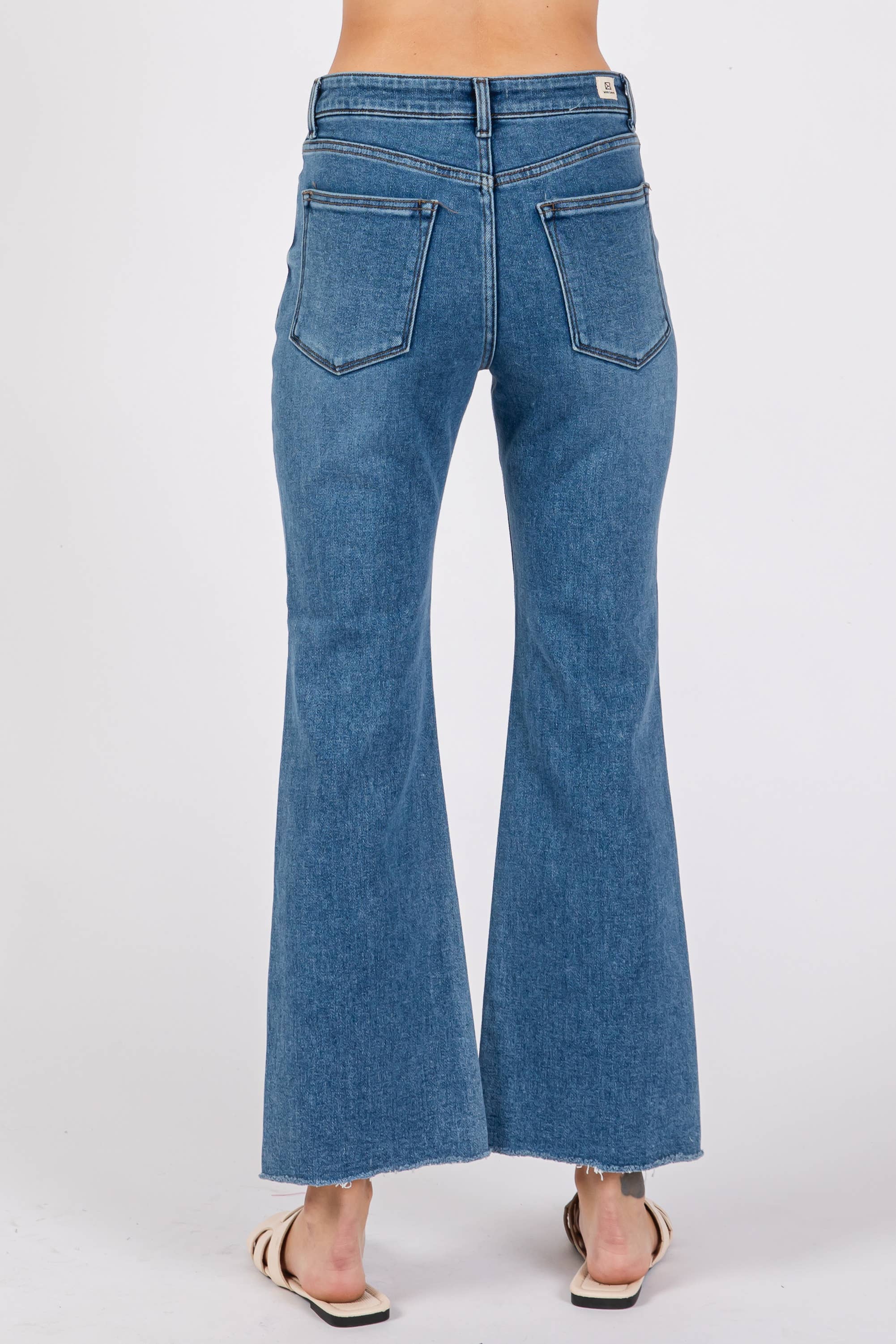 Back view of a person wearing Medium Sicily Jean Square Pocket flared blue denim jeans with raw hem edges