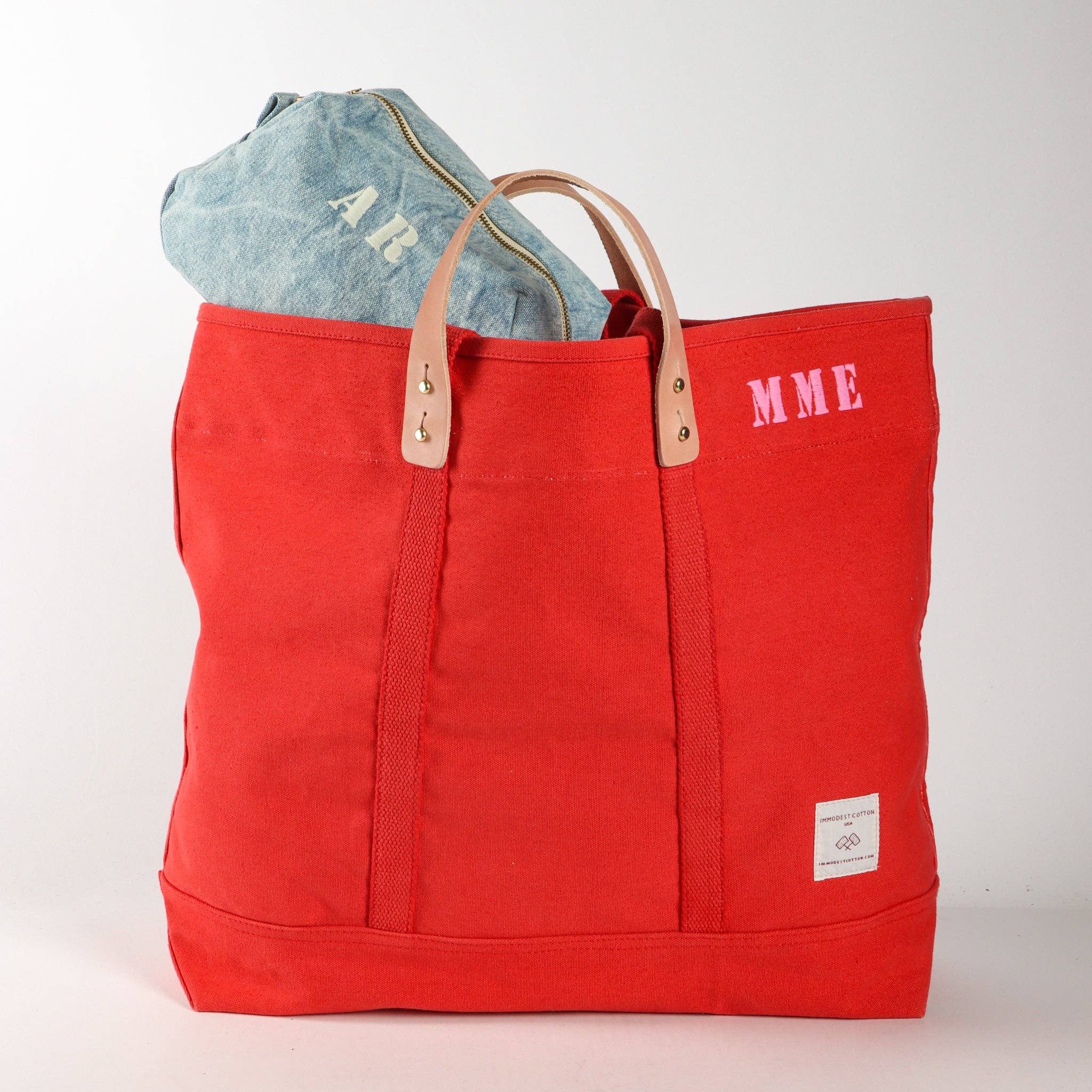 Large East West Tote | Persimmon in bright orange canvas with leather handles and a denim pouch inside against white background